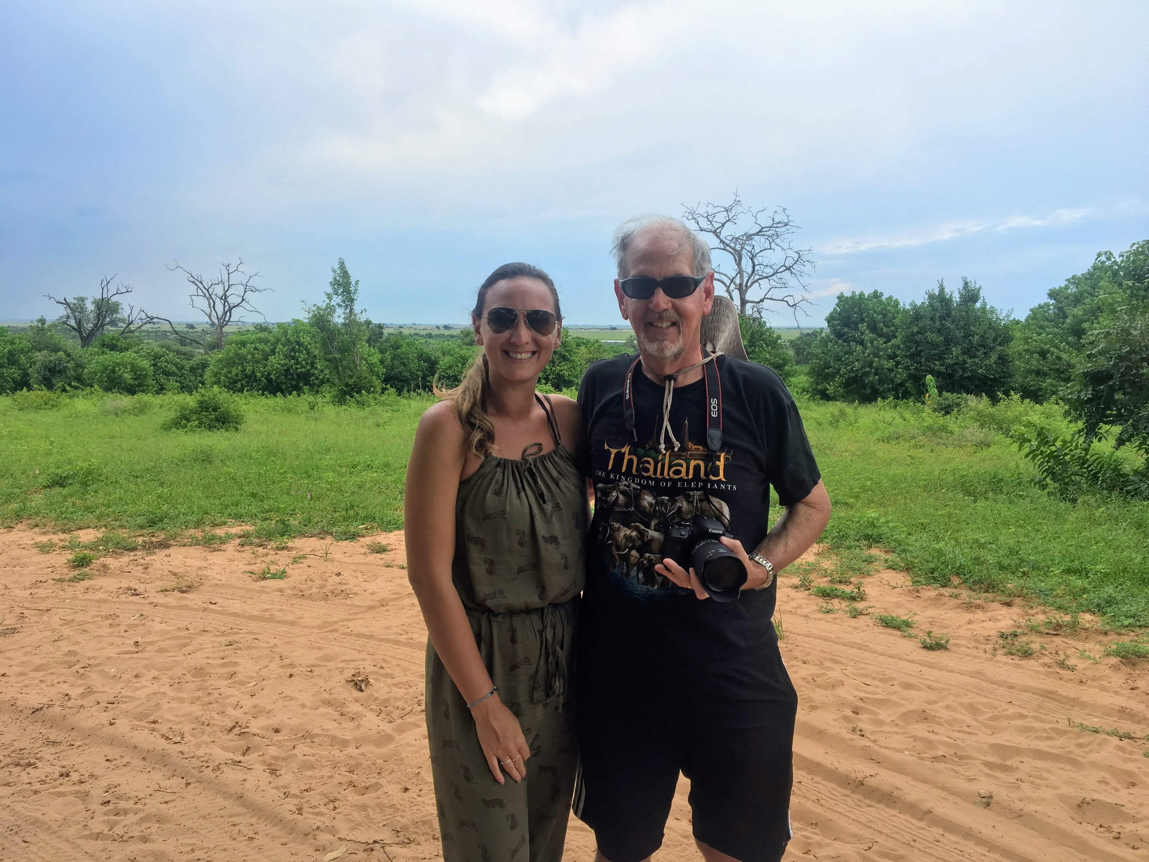 Travelers smile happily against a vibrant green backdrop in Thailand during daylight.