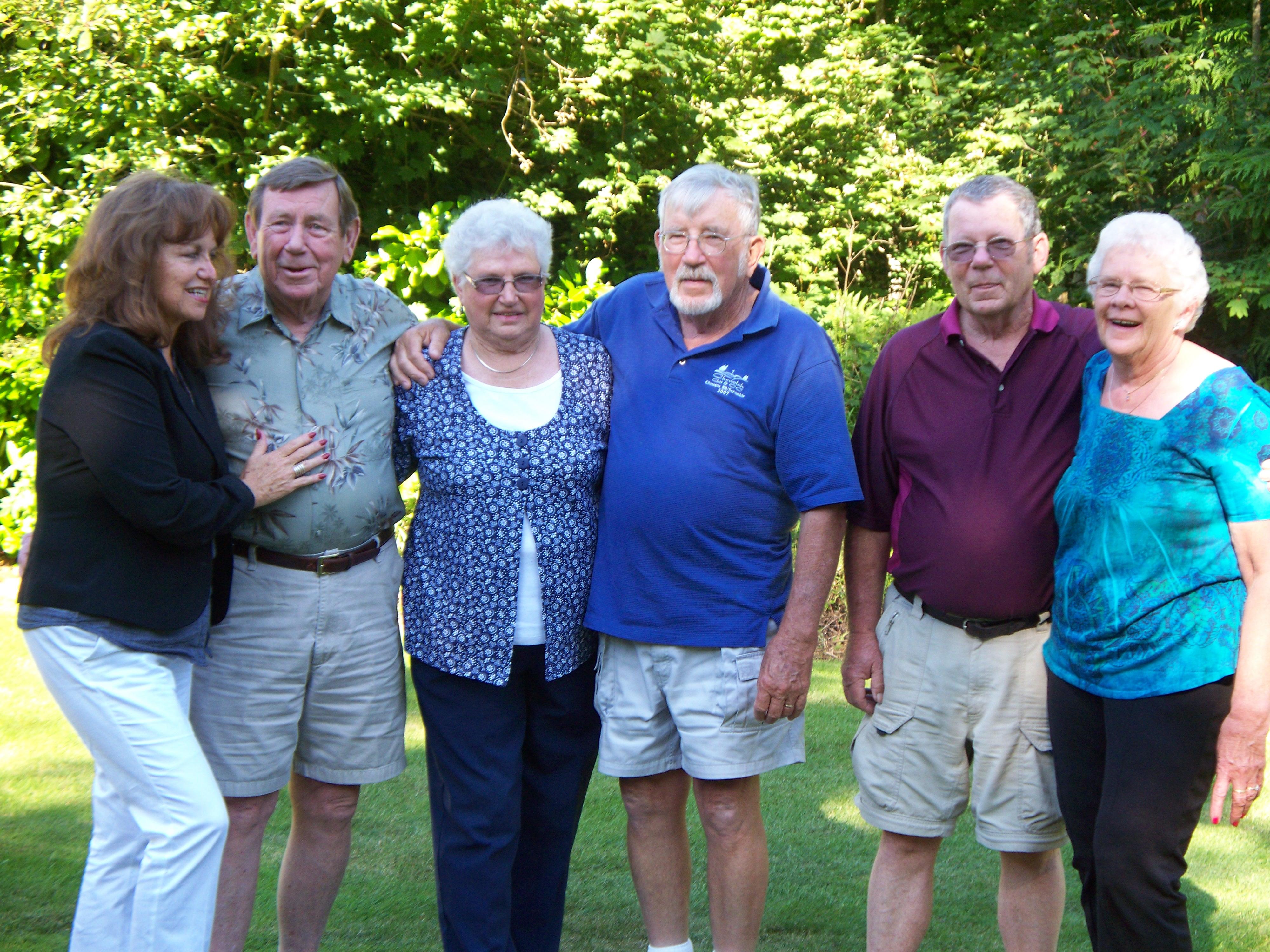 Six friends gather in a lush garden, sharing laughter and good times on a sunny afternoon.