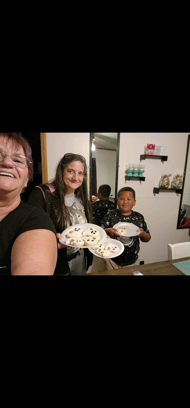 A group gathers around, smiling and sharing sweet treats in a warm, inviting kitchen.