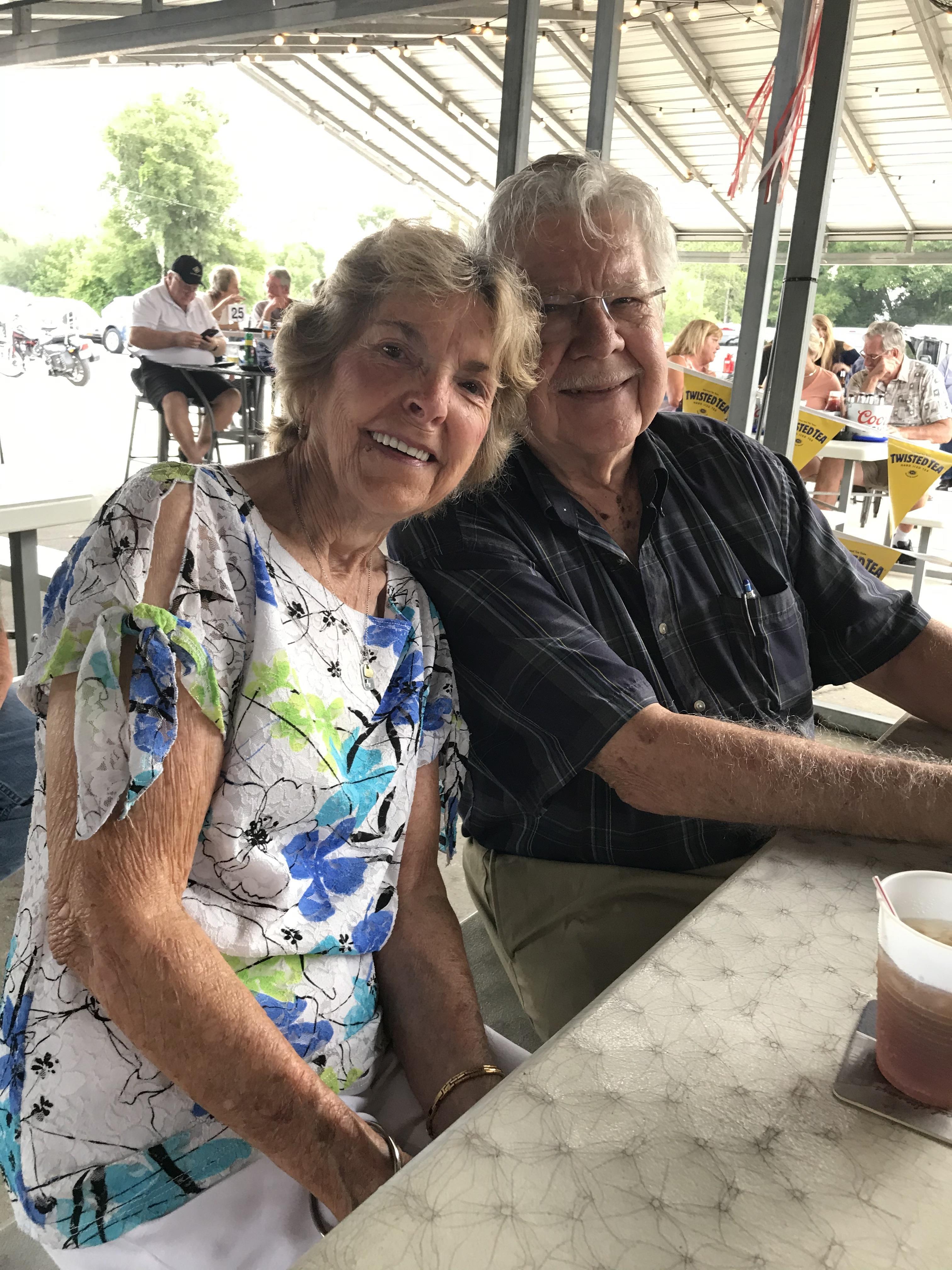 Happy couple enjoys a warm day together at an outdoor dining table.
