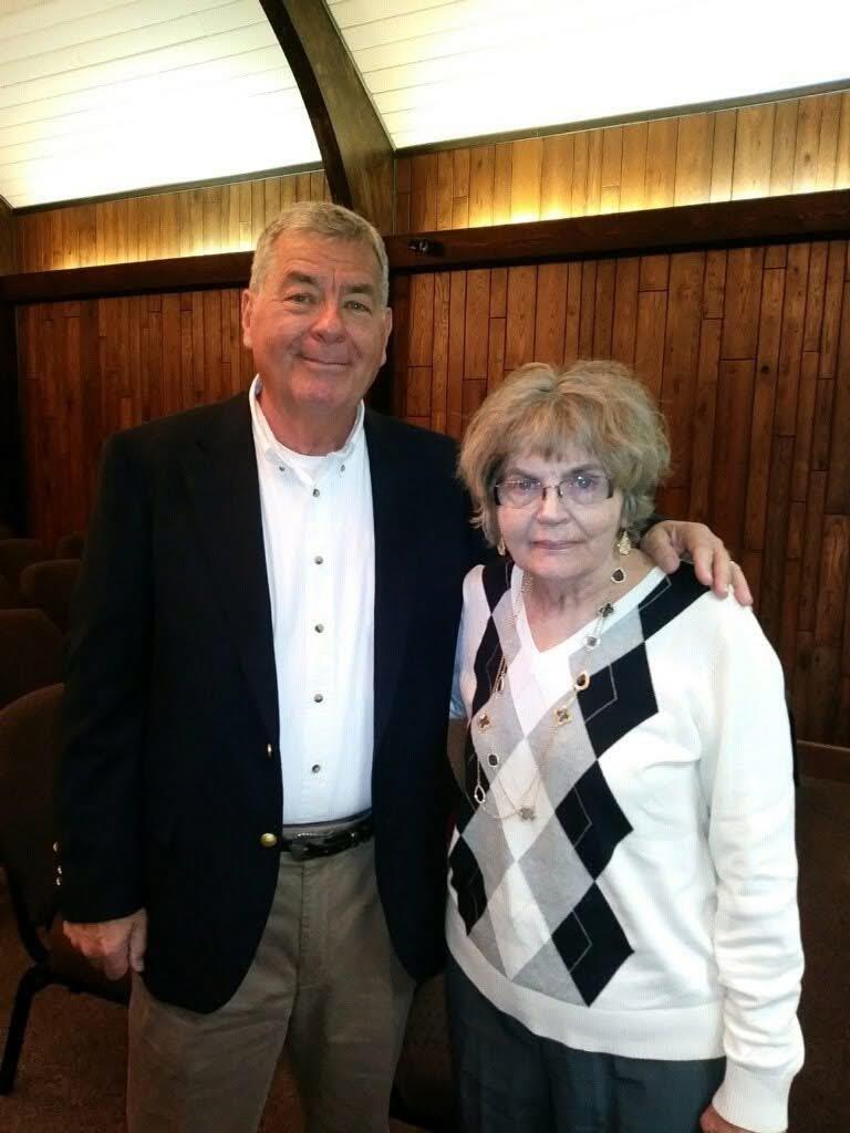Two individuals pose happily in an intimate indoor venue, showcasing friendship and warmth.