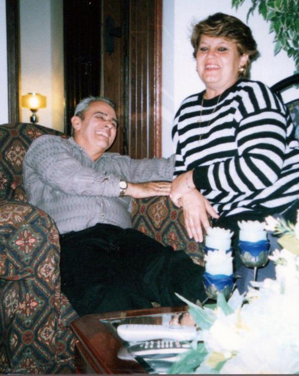 Two friends share a lighthearted moment on a couch, surrounded by warm lighting and home decor.
