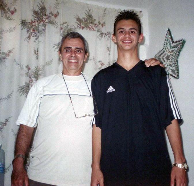 Two men stand together smiling in a brightly lit room, capturing a joyful moment at home.