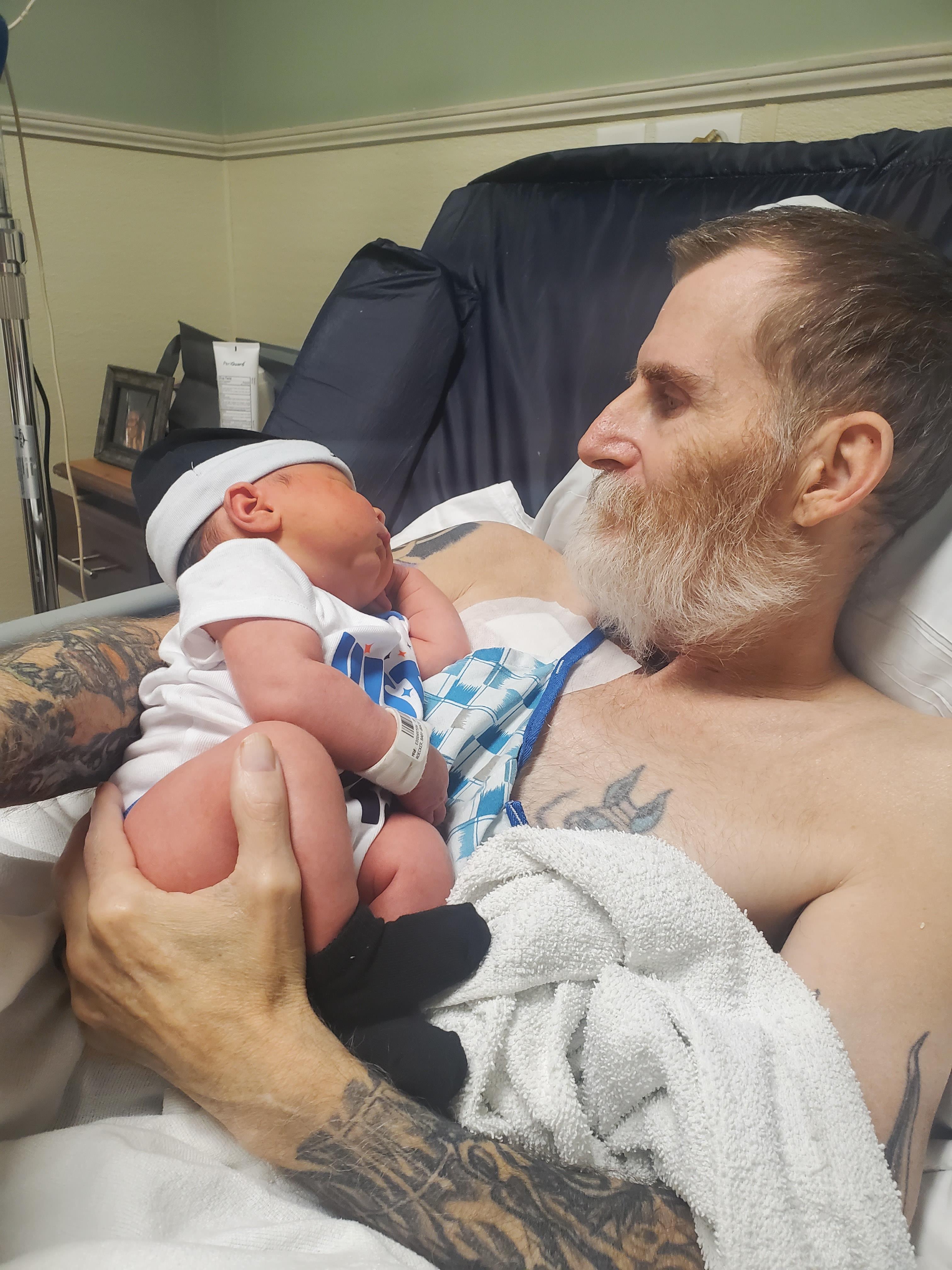 New father cradles his baby in a hospital room, sharing a heartfelt moment of connection.