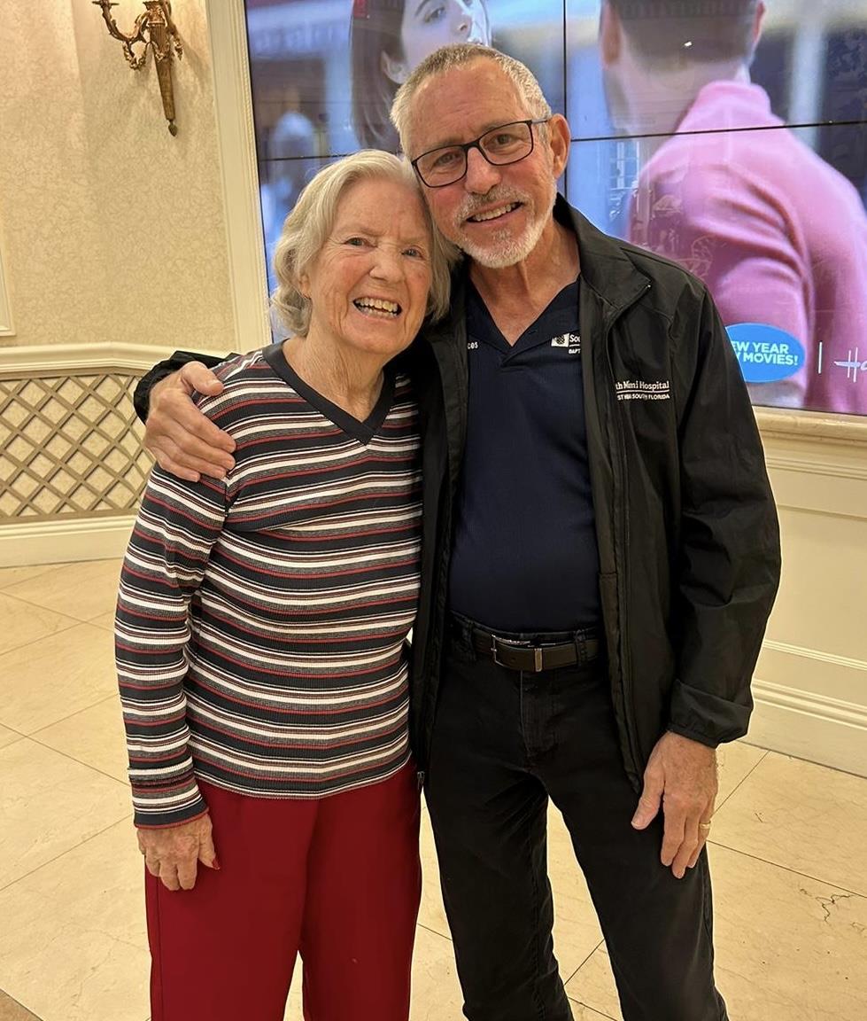 Two smiling seniors embrace joyfully in a warm, inviting environment filled with light.