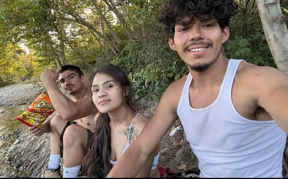 Friends sit by the riverbank, enjoying the sun and each other's company while posing for a fun shot.