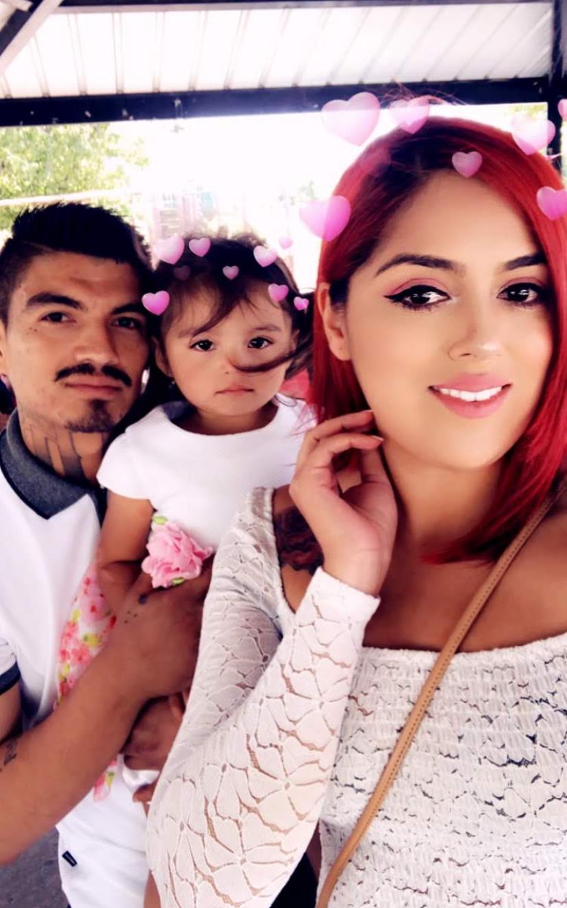 A couple poses with their adorable daughter, basking in the warm sunlight.
