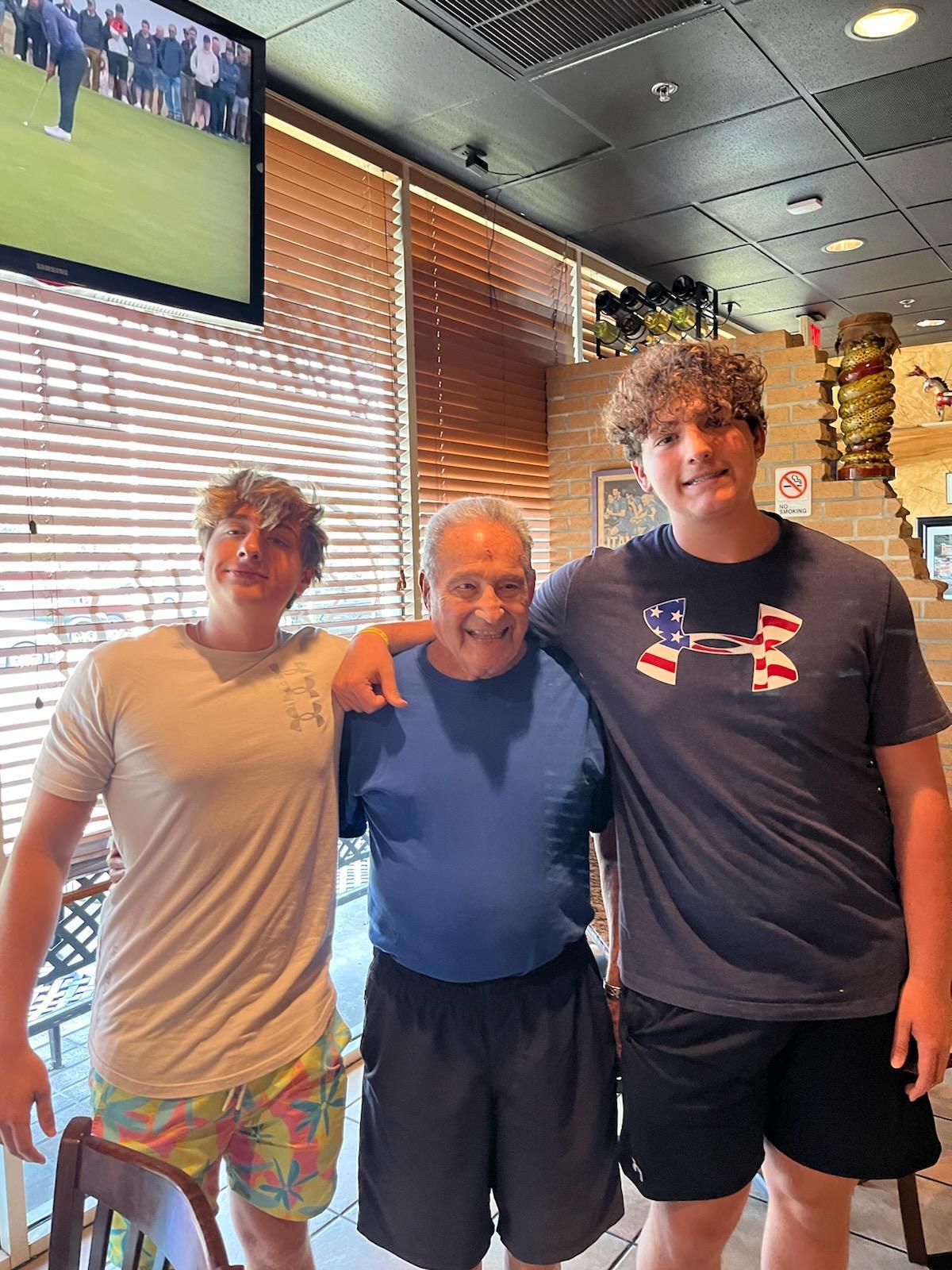 Three men pose together in a lively restaurant, enjoying their time and sharing smiles.