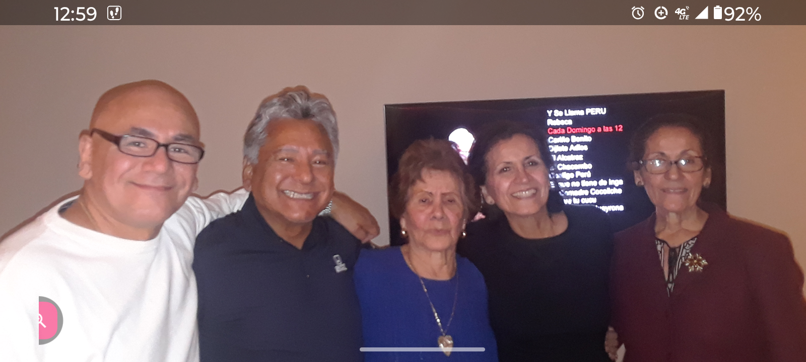 Five family members joyfully pose together in a warm indoor setting, celebrating companionship.