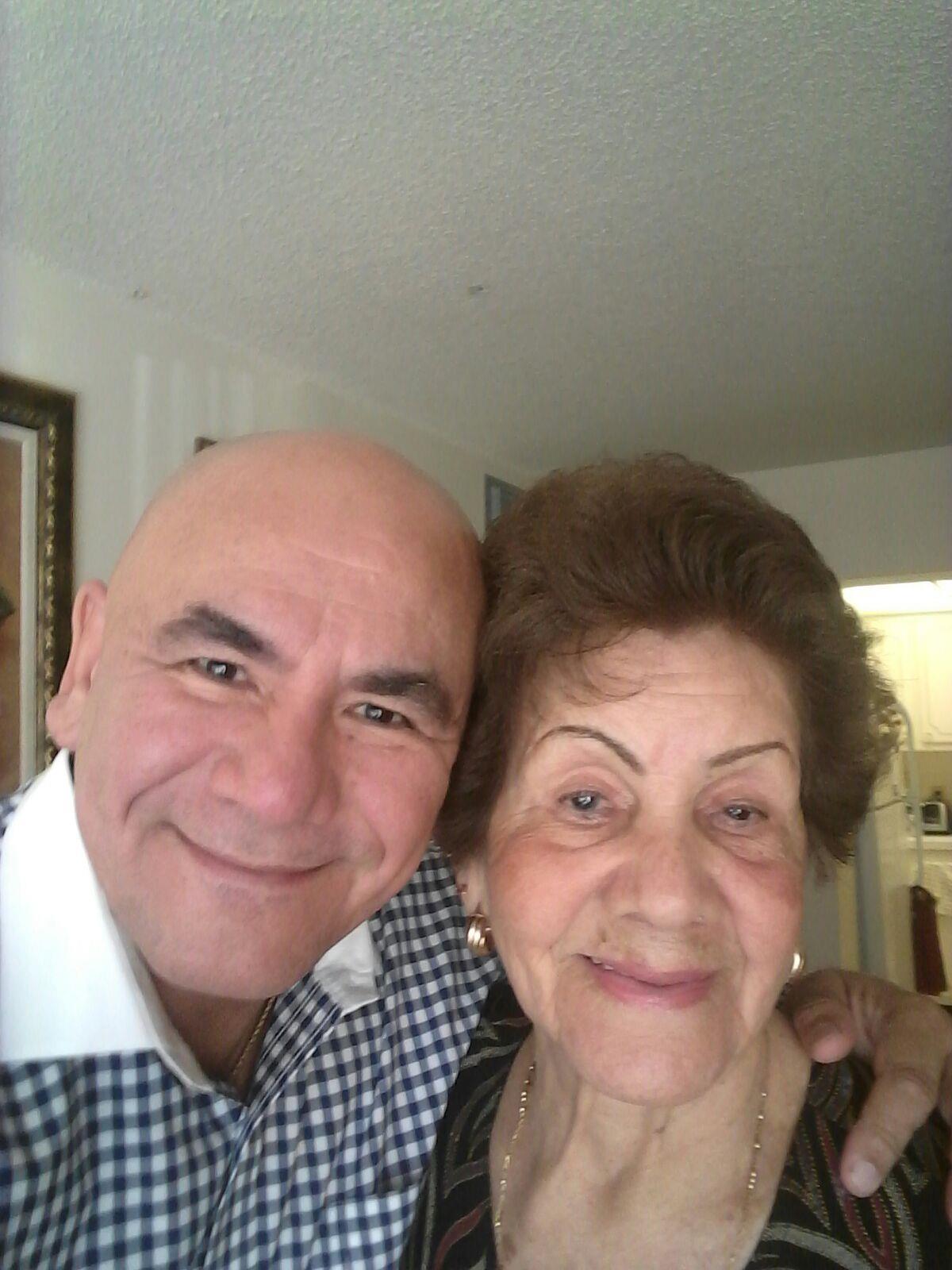 A man smiles warmly with an older woman in a cheerful embrace, highlighting their bond.