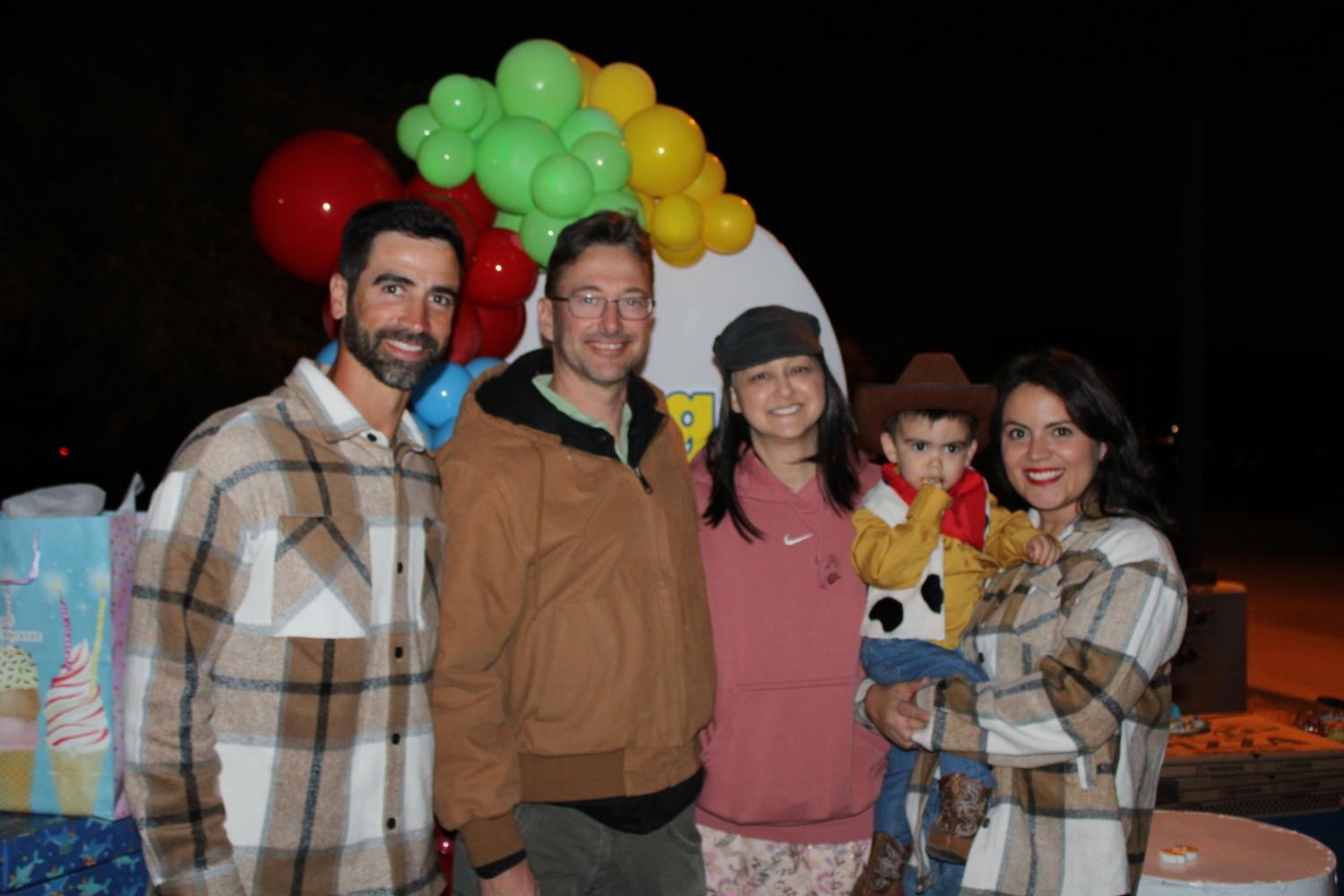 A group of friends and their kids enjoy a fun evening party with colorful decorations.