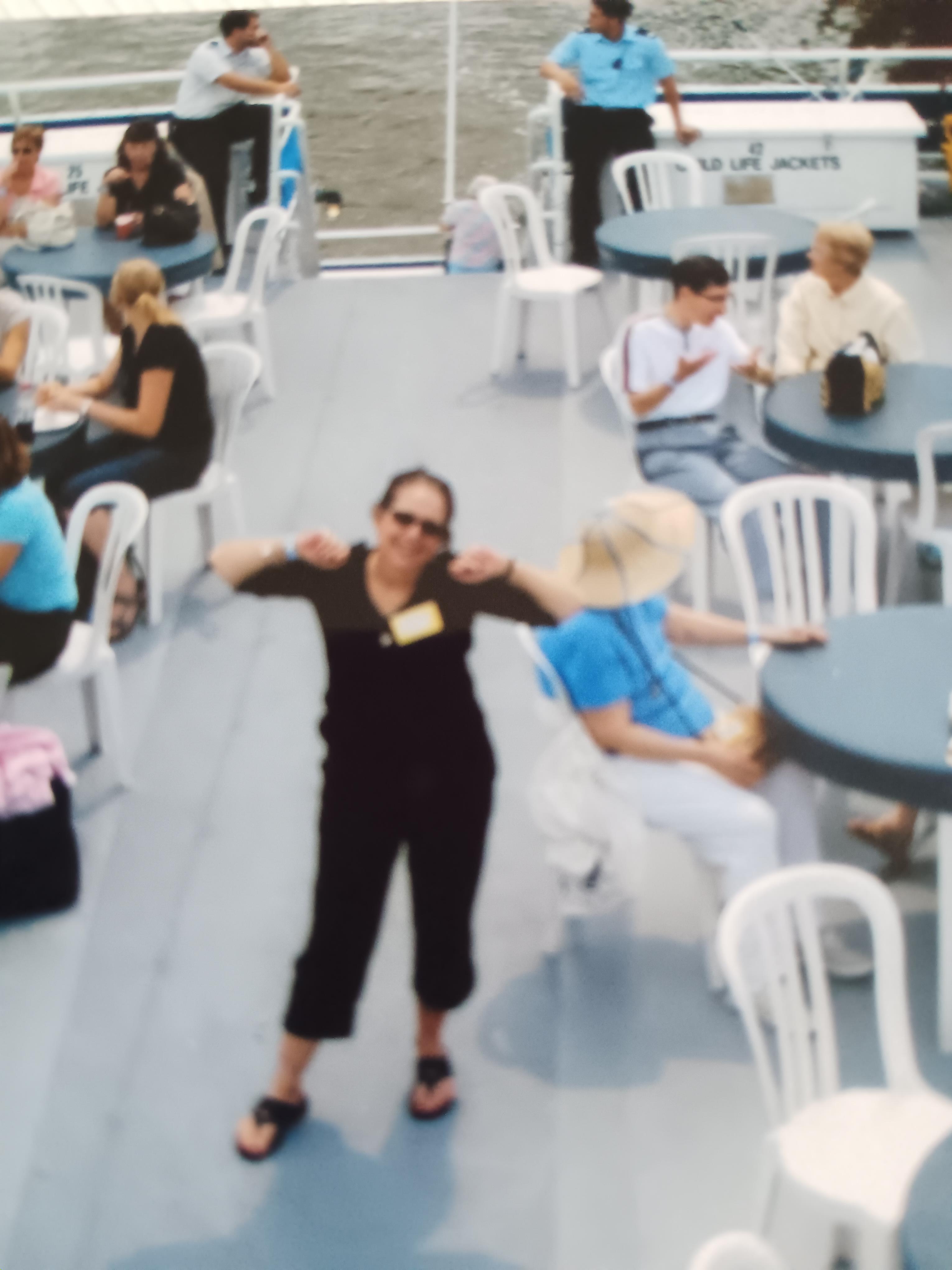 People socialize and relax on a boat deck, enjoying a sunny day by the water.
