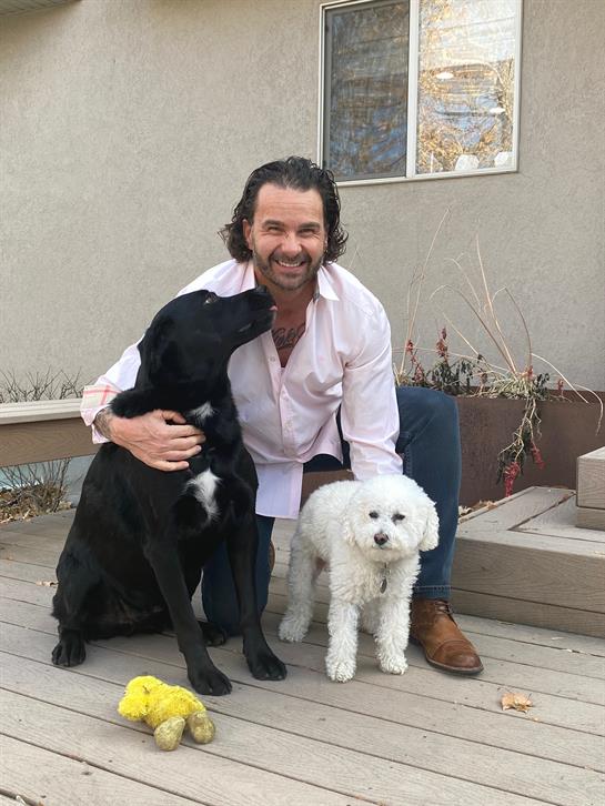 A man sitting with two dogs