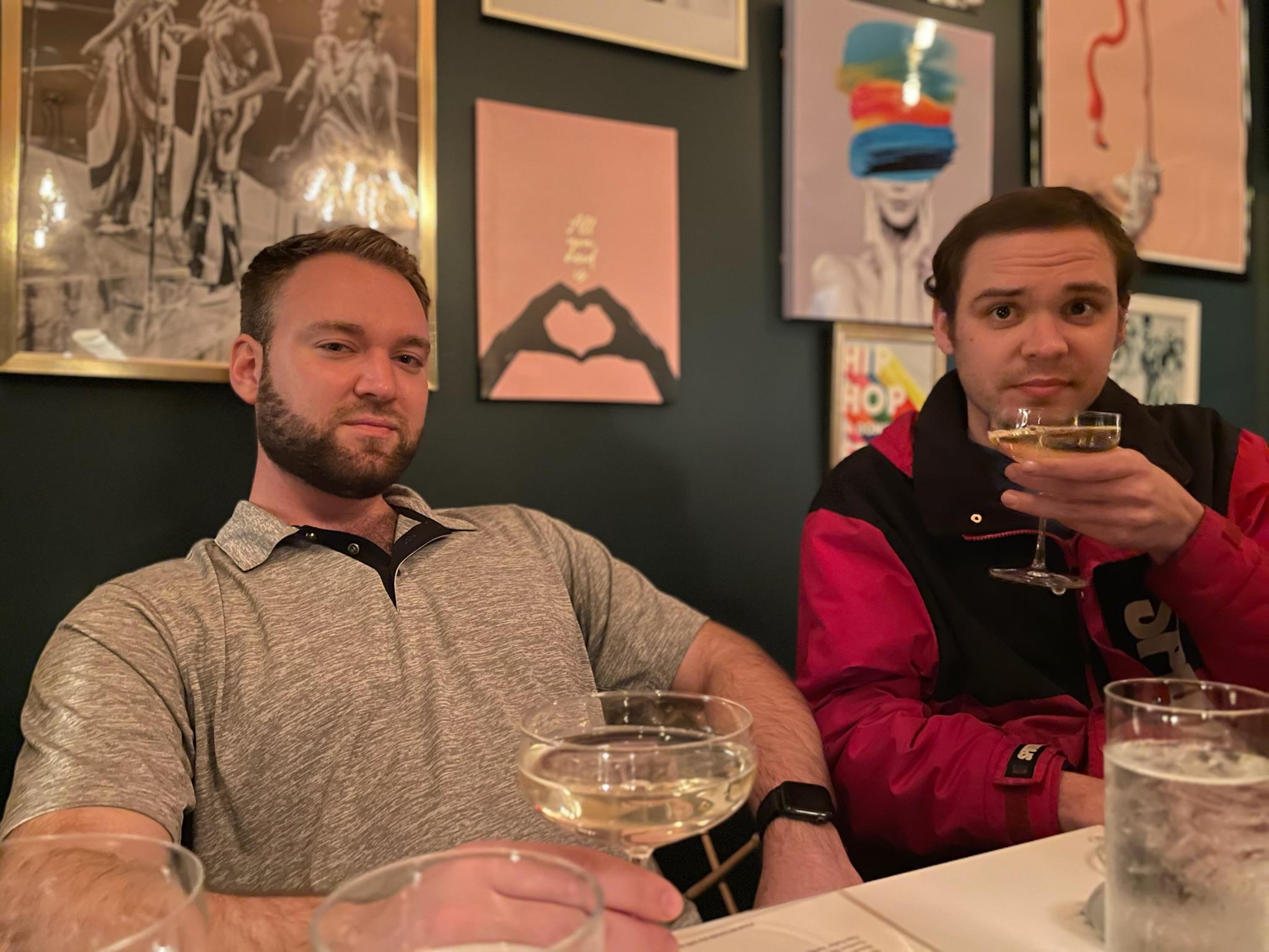 Two friends at a stylish bar enjoy cocktails together.