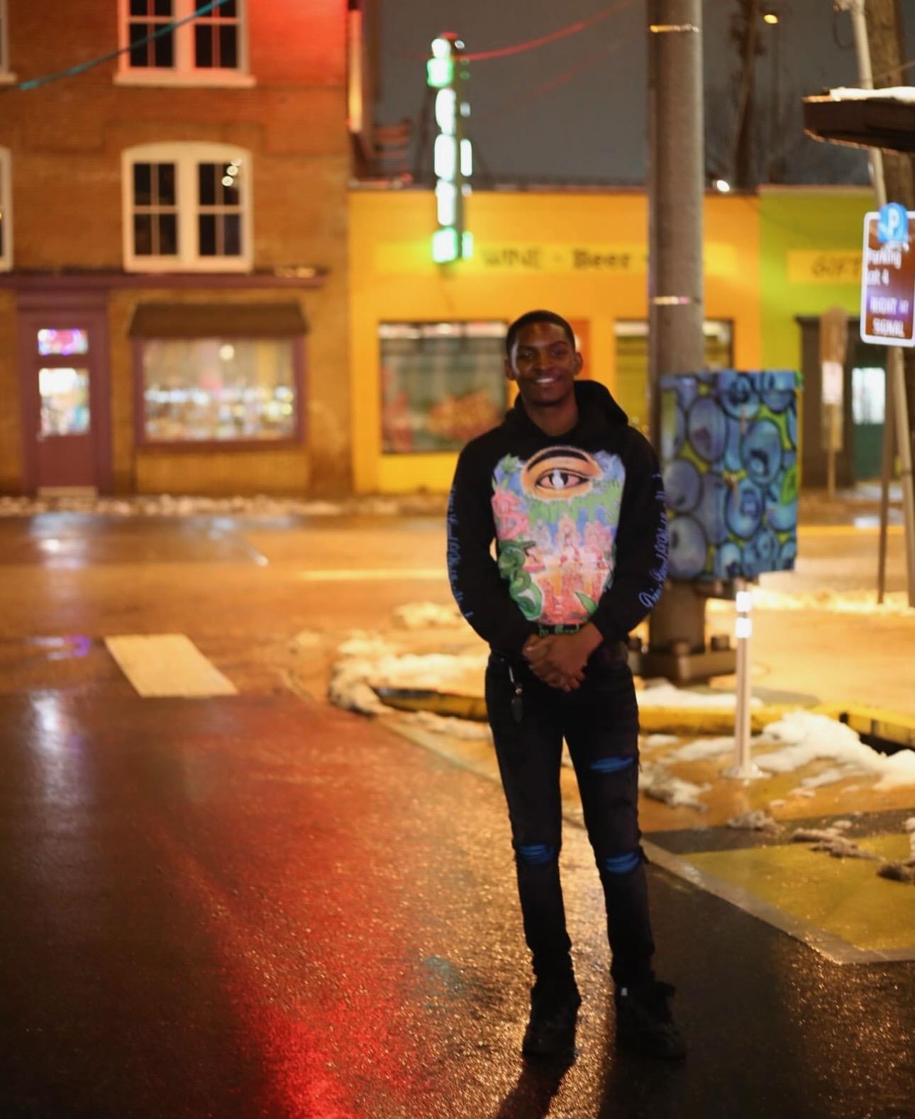A man standing on a street holding a painting