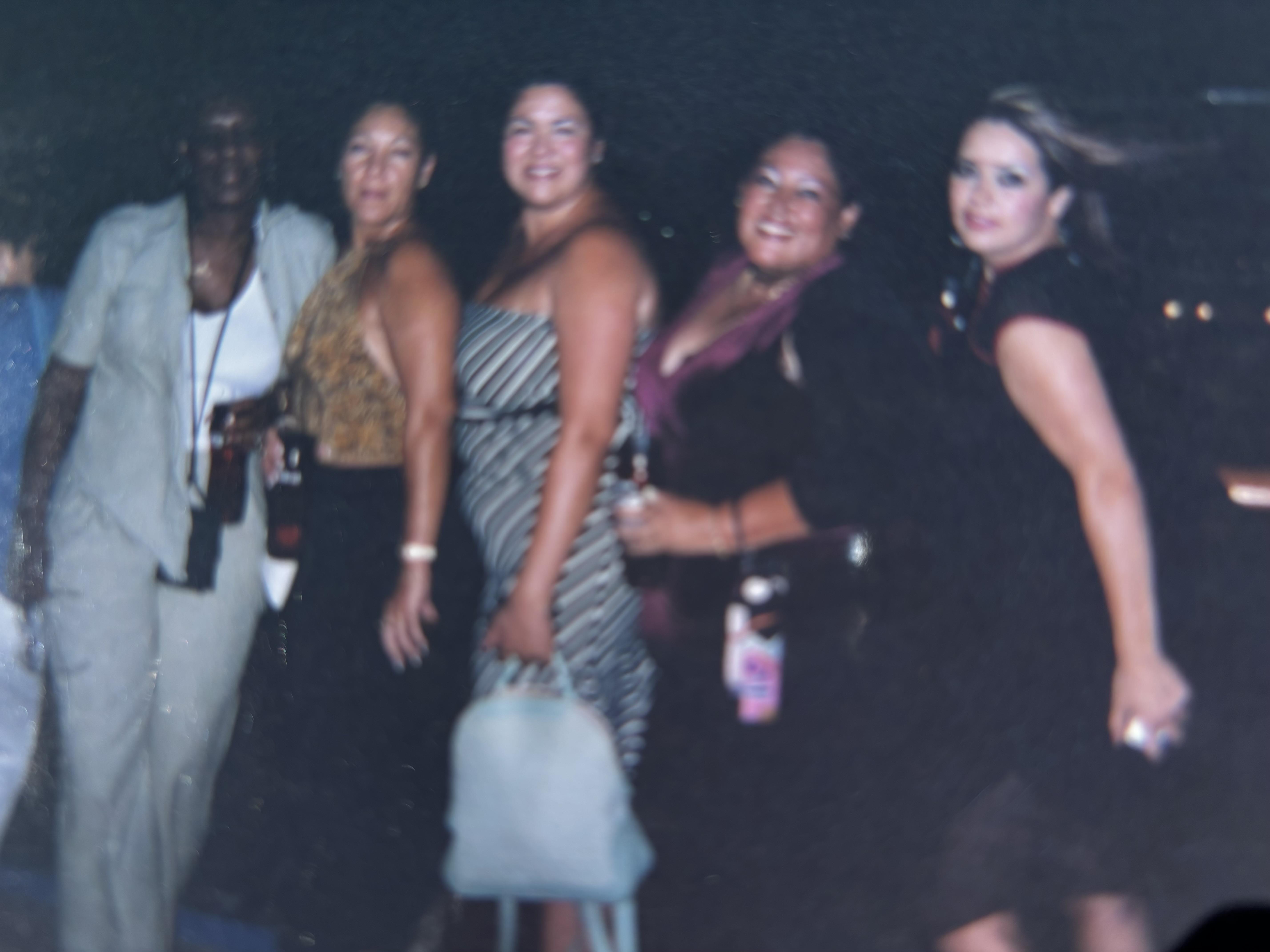 A group of women dressed elegantly socialize during a lively summer evening party.