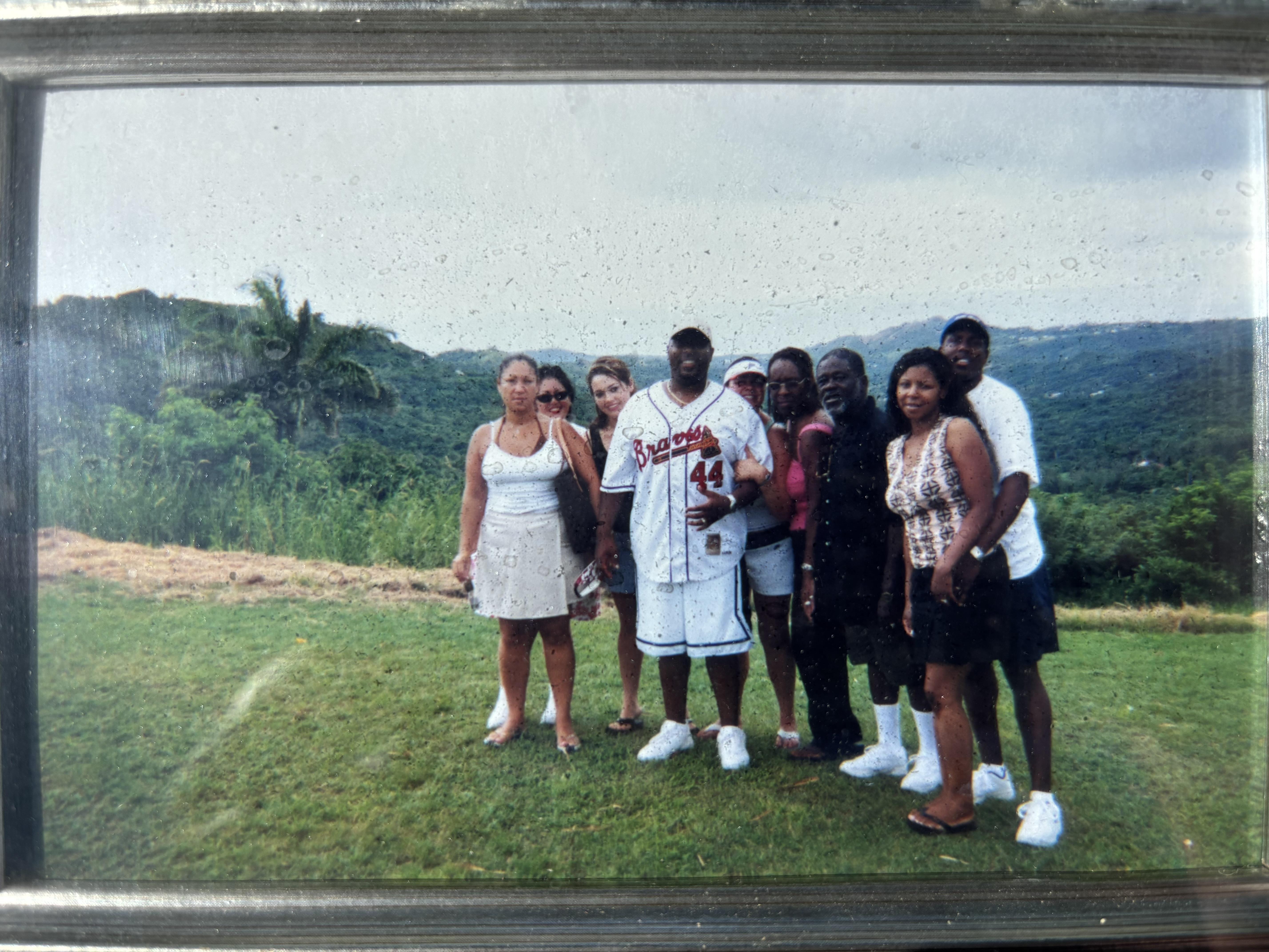 Six friends gather together on a grassy hillside, enjoying a cloudy day and stunning views.