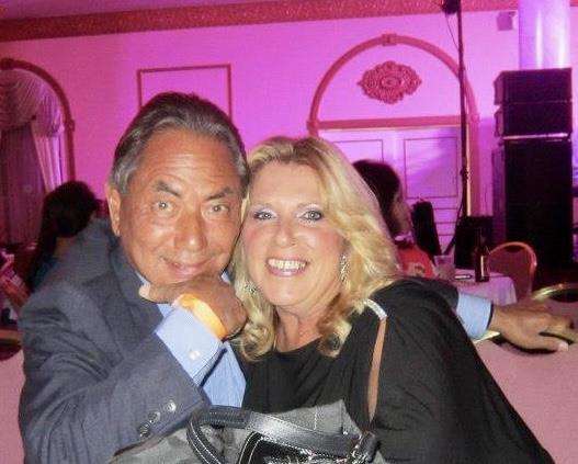 A couple smiles and poses together, exuding joy during a vibrant gathering with colorful lighting.