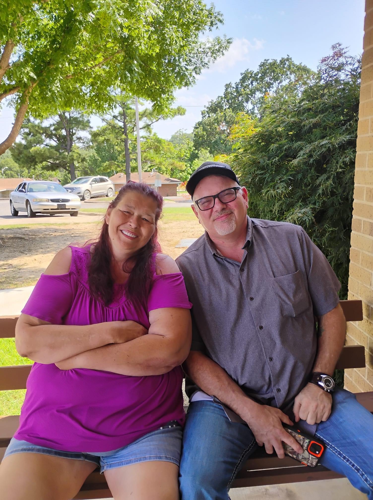 Two friends sitting on a porch bench in bright sunlight, sharing a moment of joy and camaraderie.