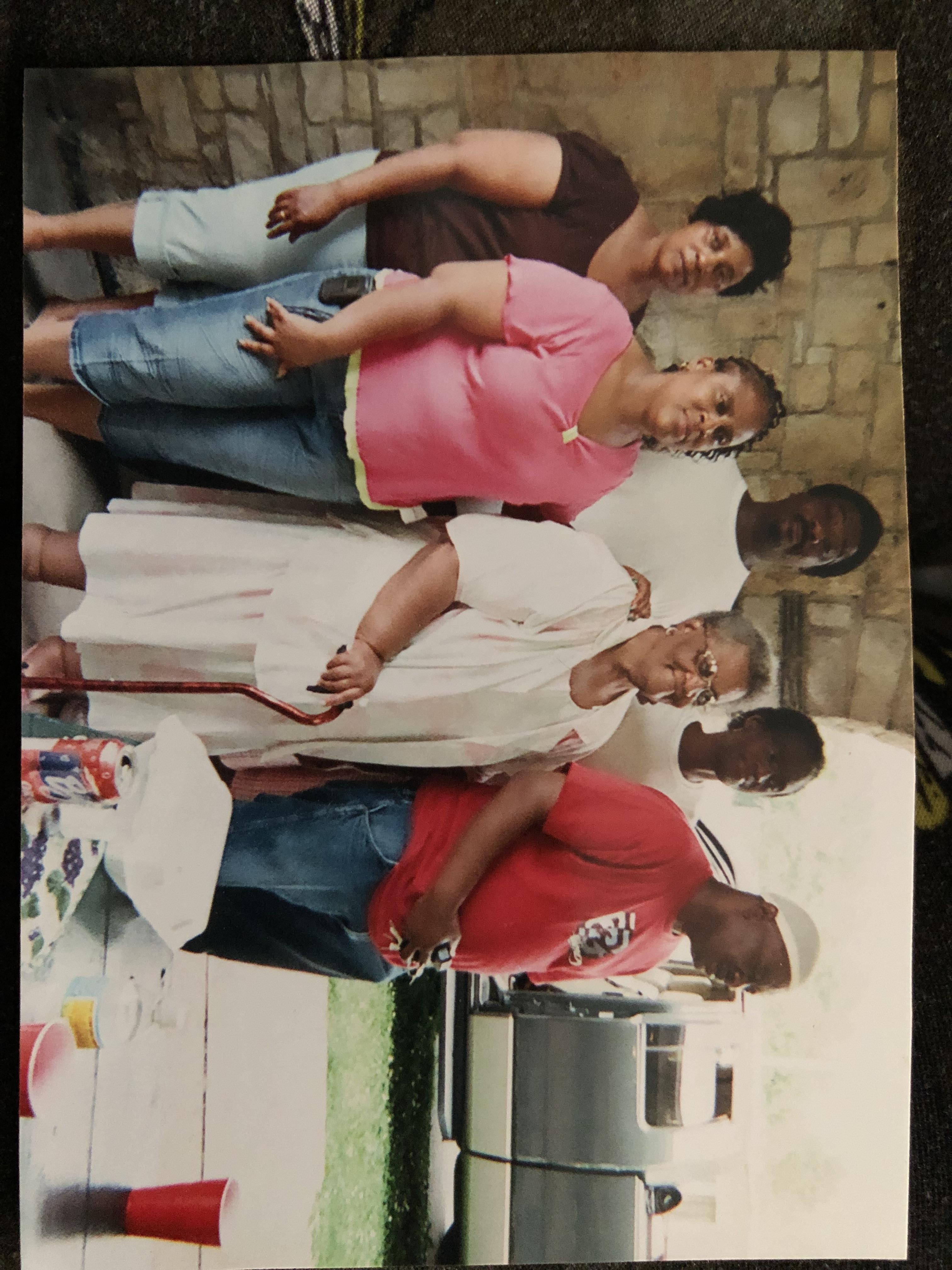 Group of family members enjoying a picnic outdoors with food, laughter, and conversation.