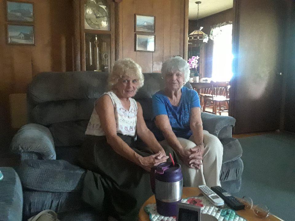 Two seniors enjoy each other's company in a comfortable living room setting, sharing stories.