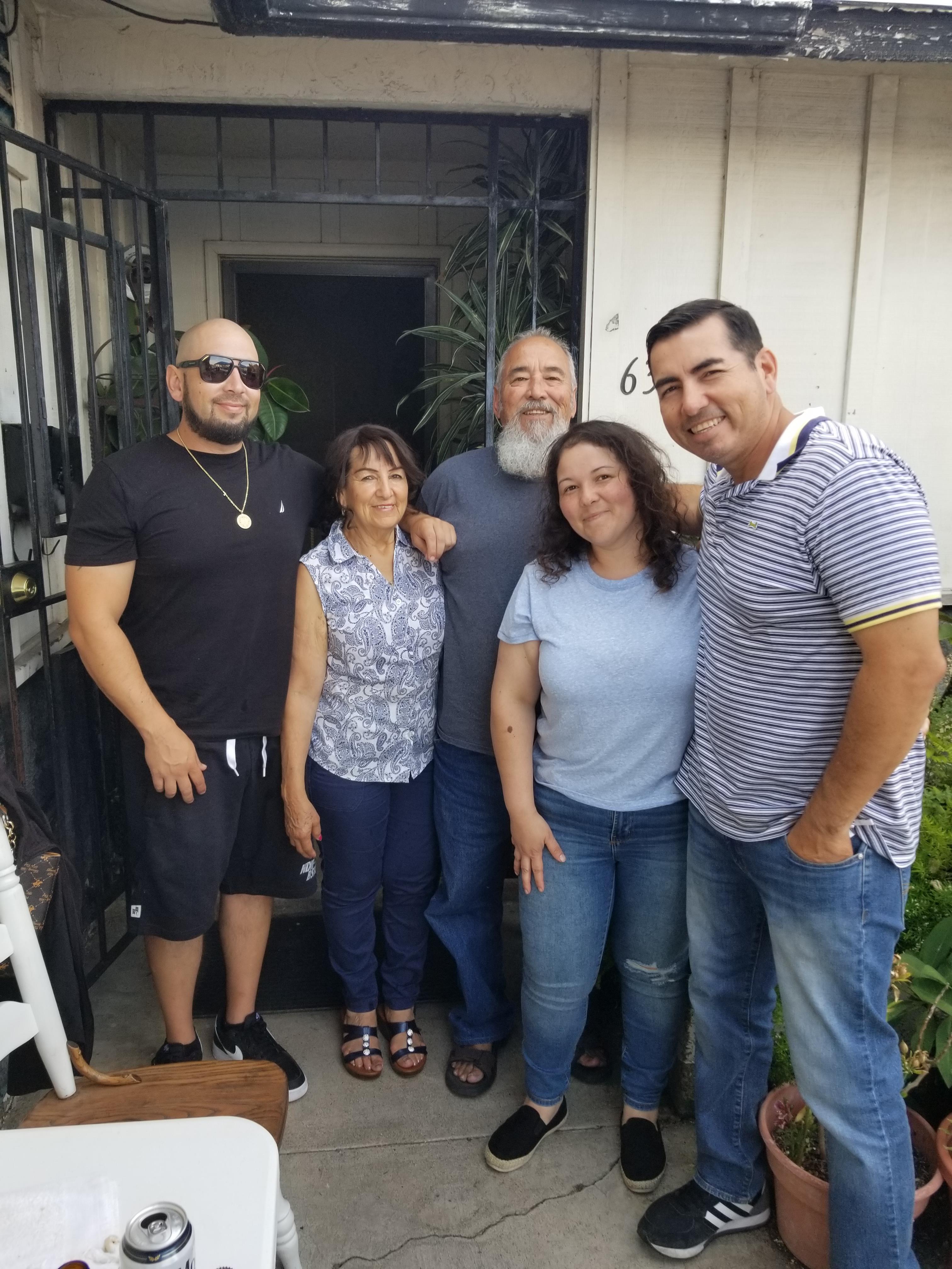 Group of five friends and family members enjoy quality time together outside their home.