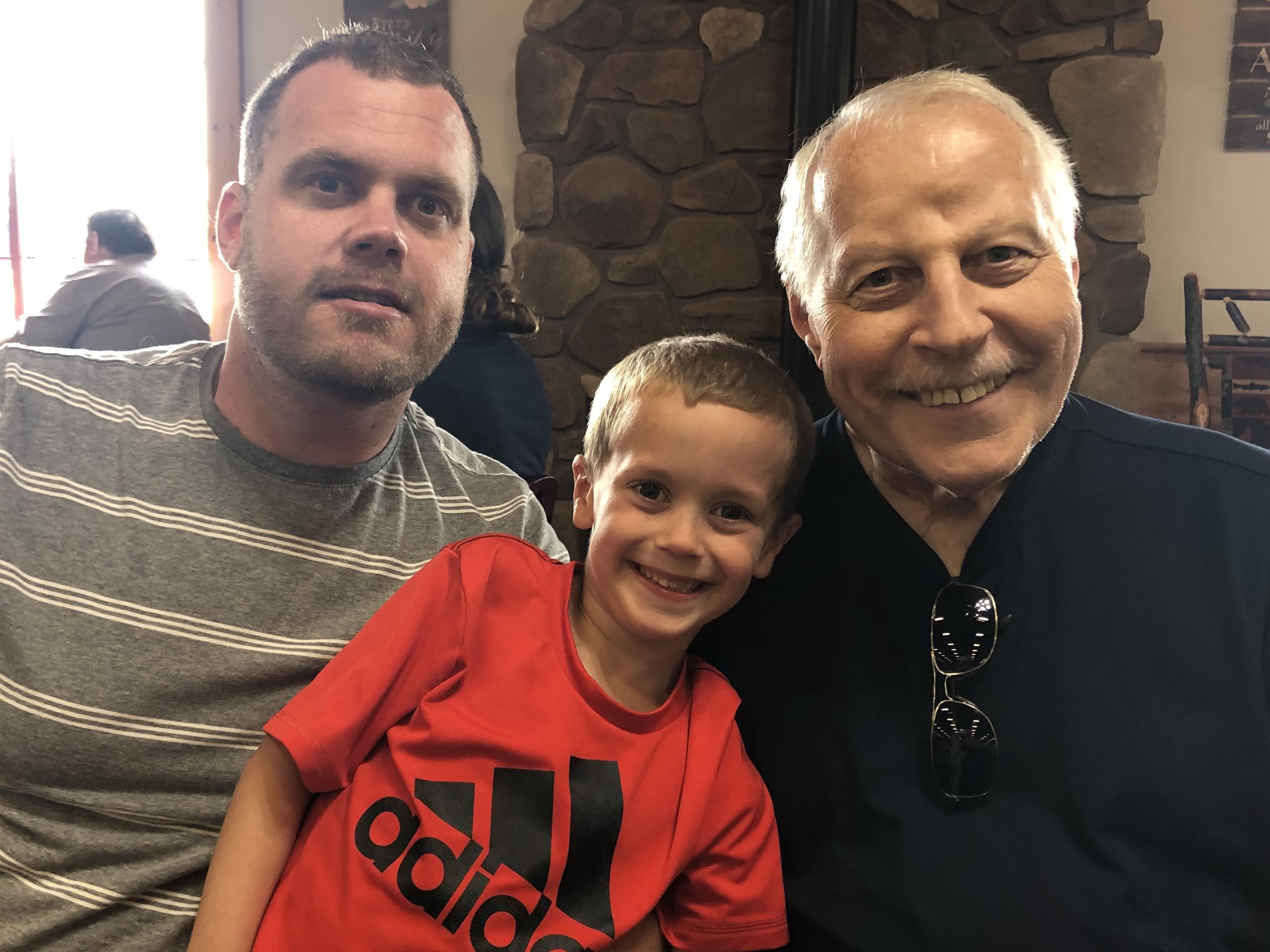 Three generations enjoy each other's company in a cheerful atmosphere within a busy restaurant.