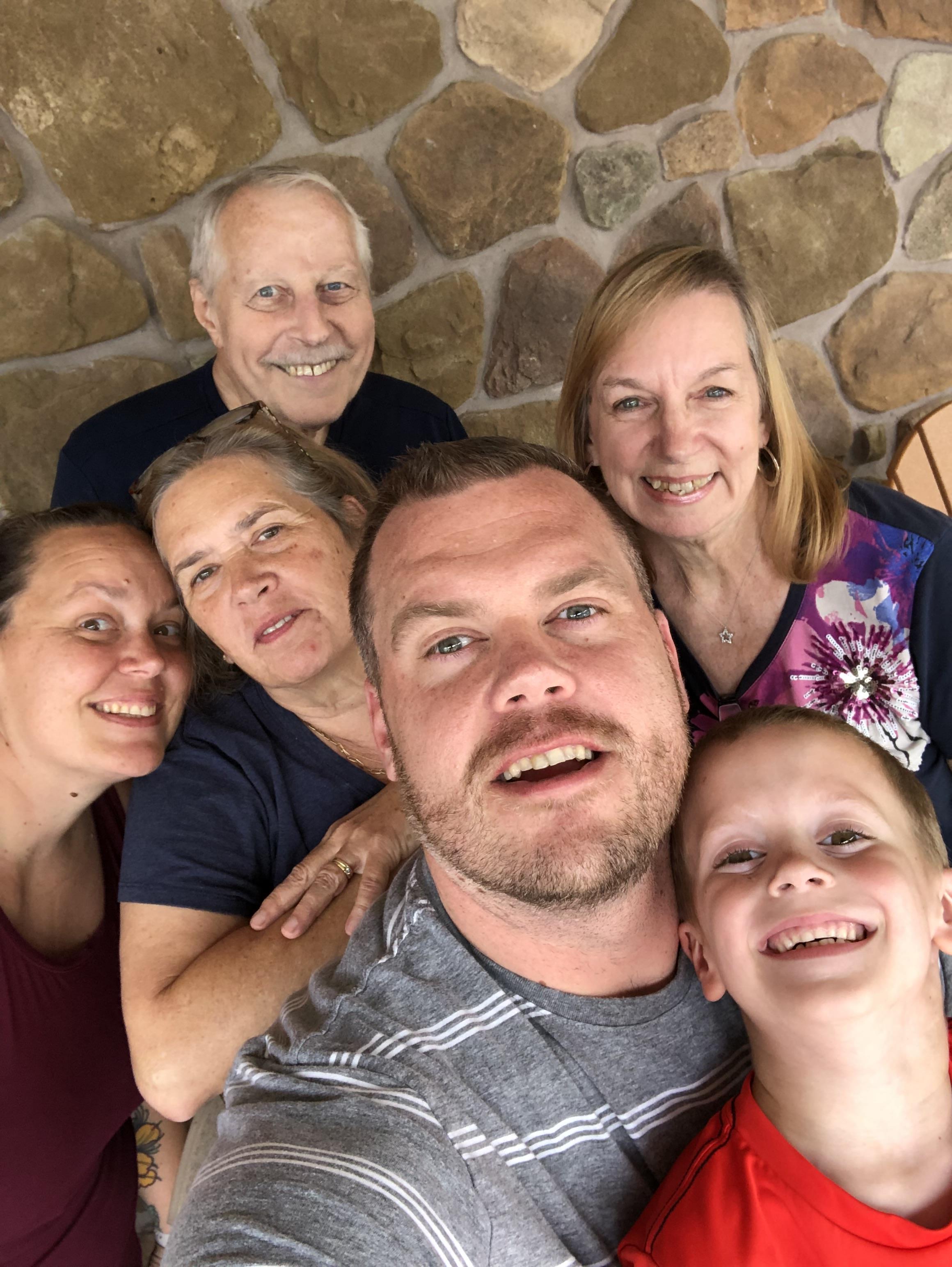 Family members gather for a joyful reunion, smiling and sharing happiness in an outdoor setting.
