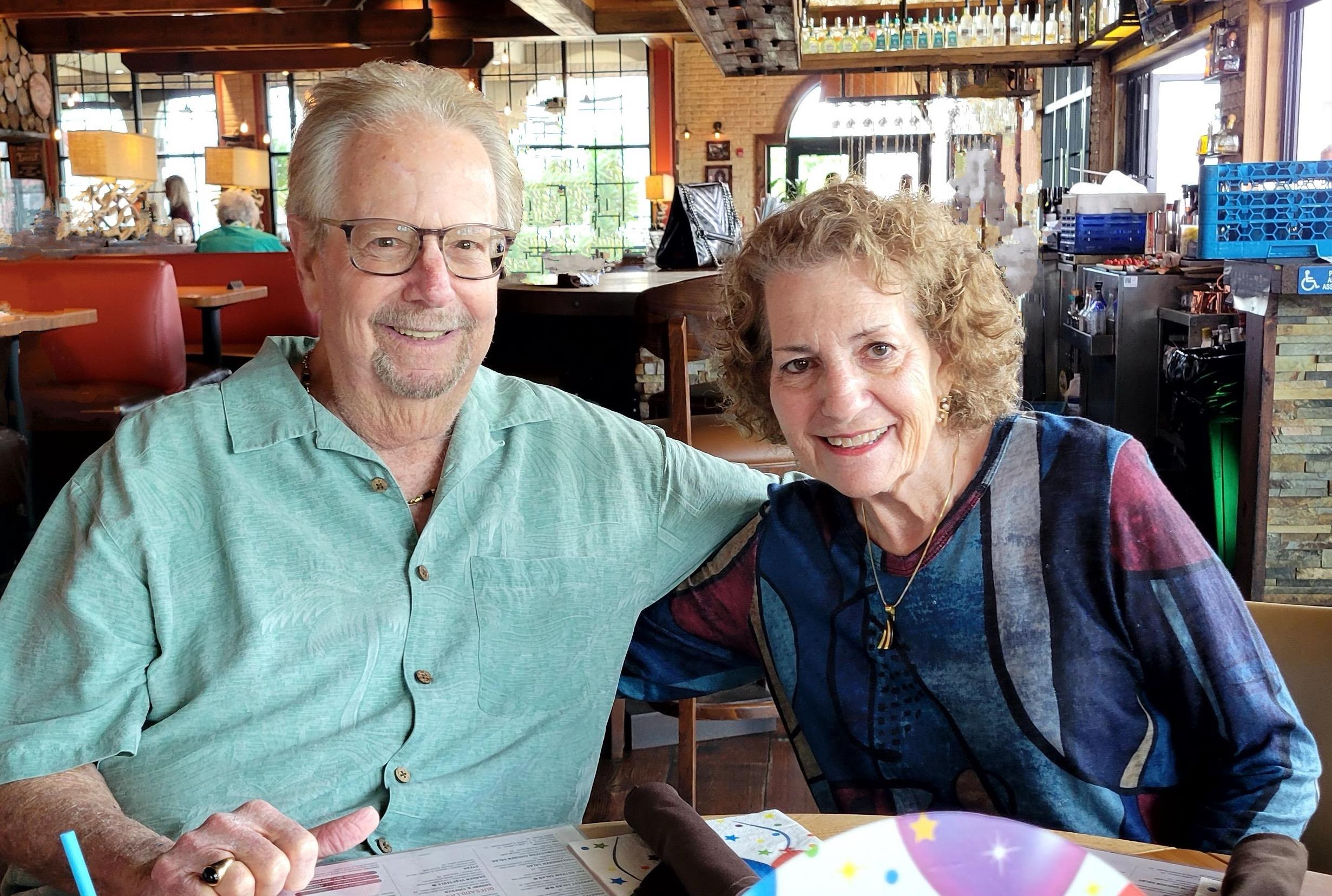 A happy couple shares a meal at a cheerful restaurant, basking in the warmth of the sun.