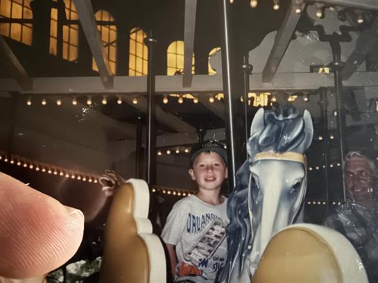 A boy sitting on a carousel horse