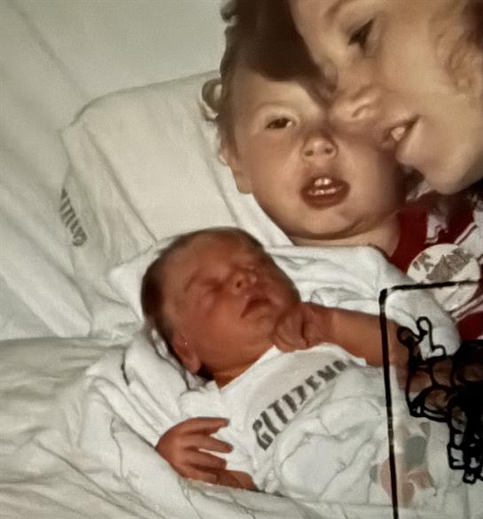 A baby lying in a bed with a woman