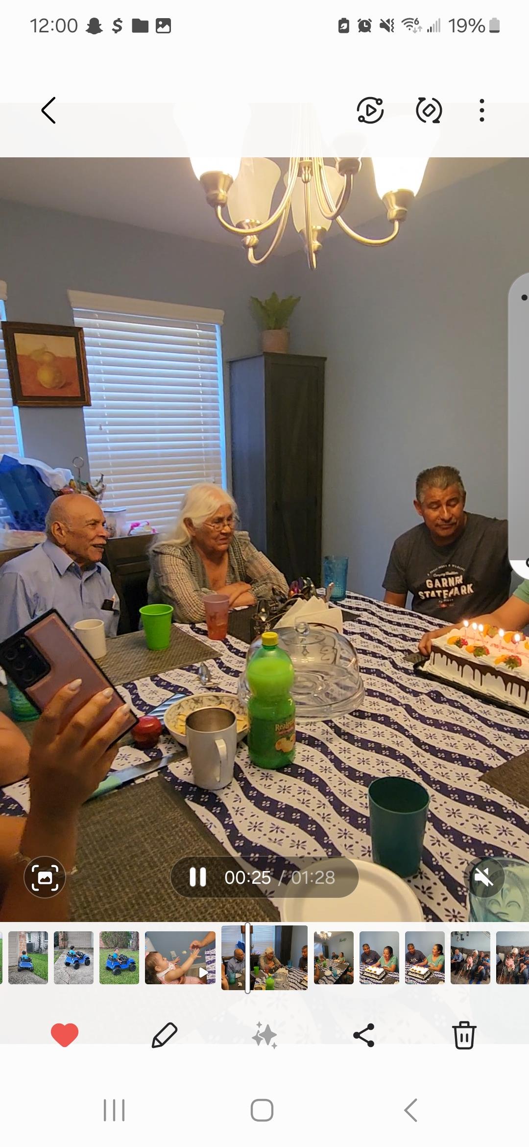 Family members gather at a table, enjoying cake and drinks during a warm evening celebration.