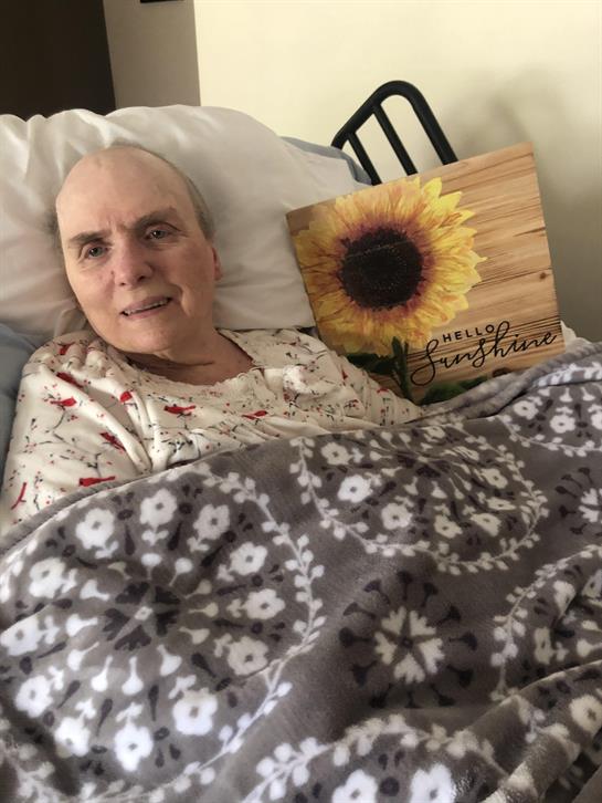 A woman lying in bed with a sign