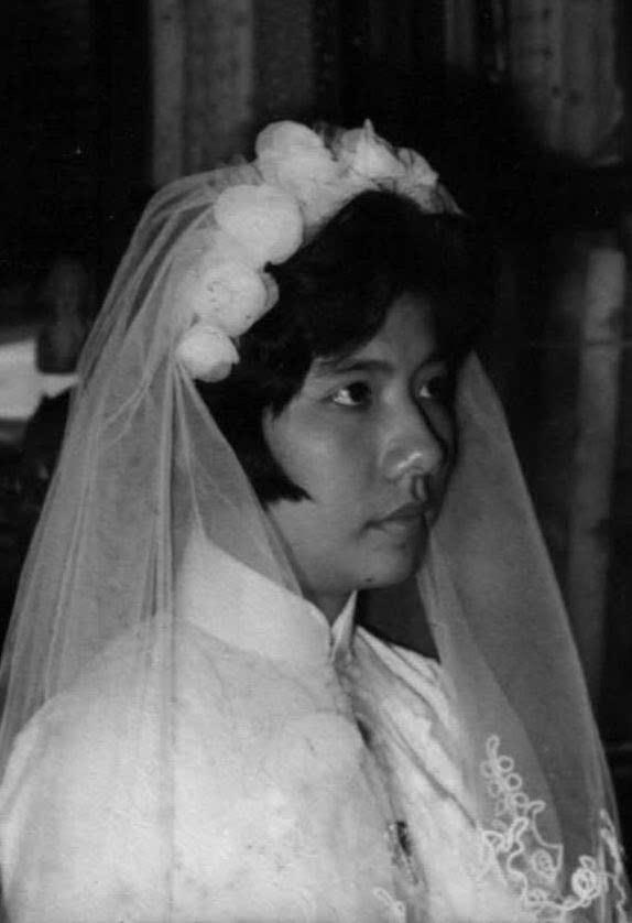 A bride, in a lace gown and veil, stands quietly in an elegant atmosphere.