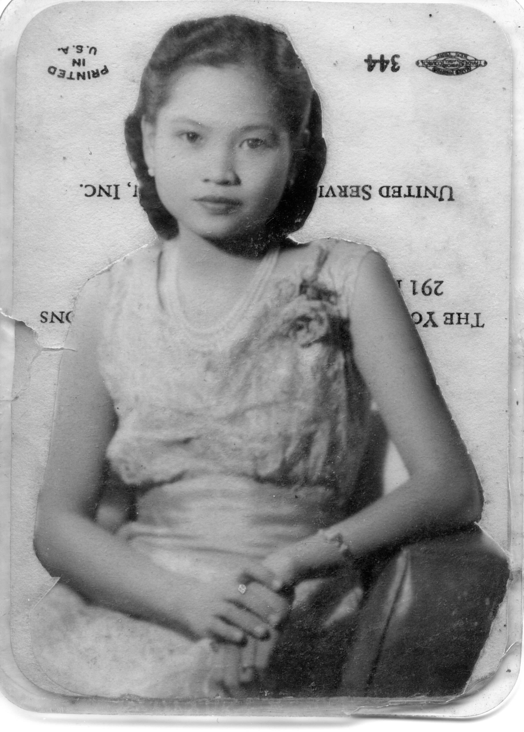 A young woman in elegant, floral attire showcases vintage charm while seated.