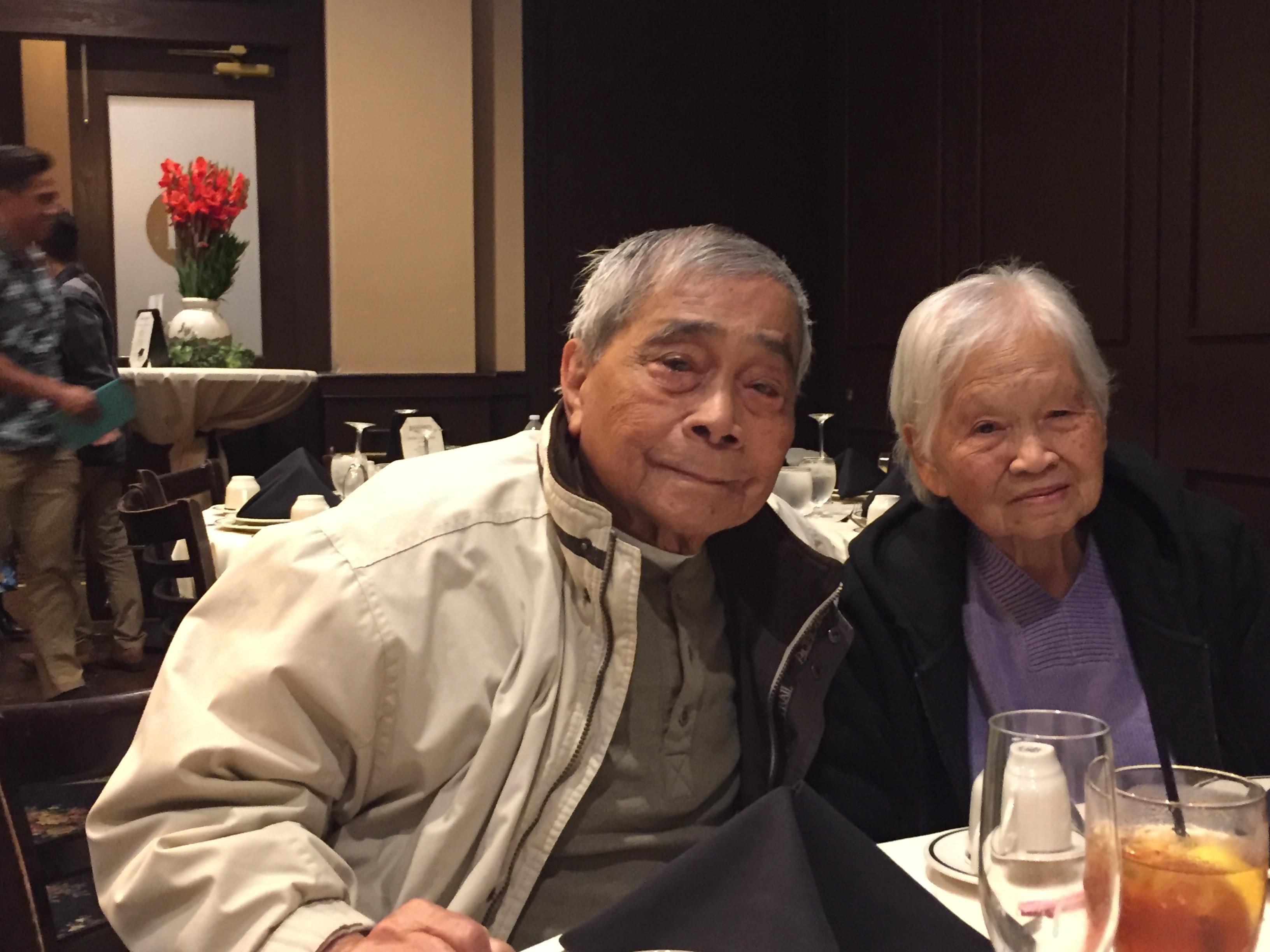An elderly couple shares a warm moment at a restaurant, savoring their meal together.