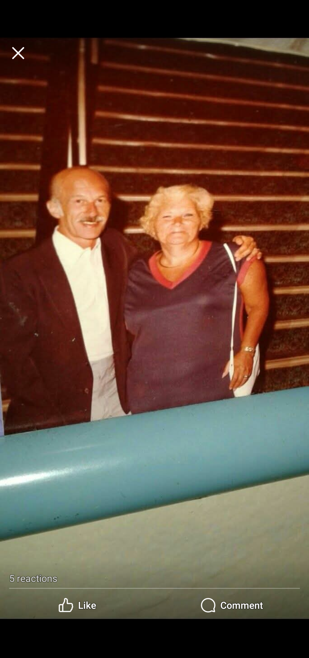 A happy couple stands on a staircase, enjoying their time at a social event together.