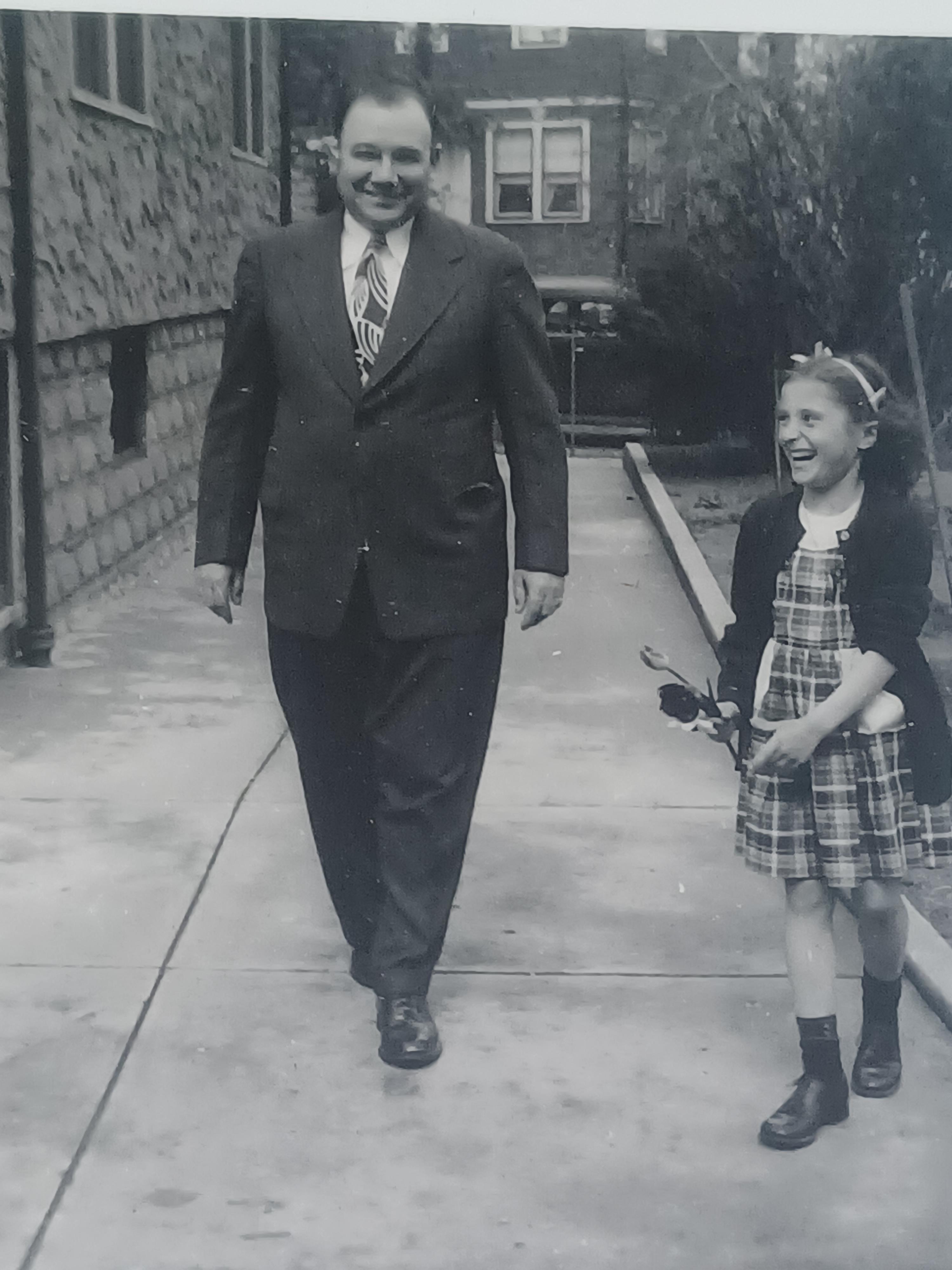 A man and girl walking on a sidewalk