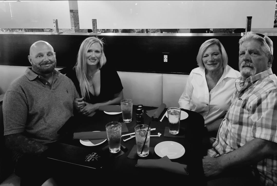 Four people engage in cheerful conversation while dining at a restaurant during the evening.