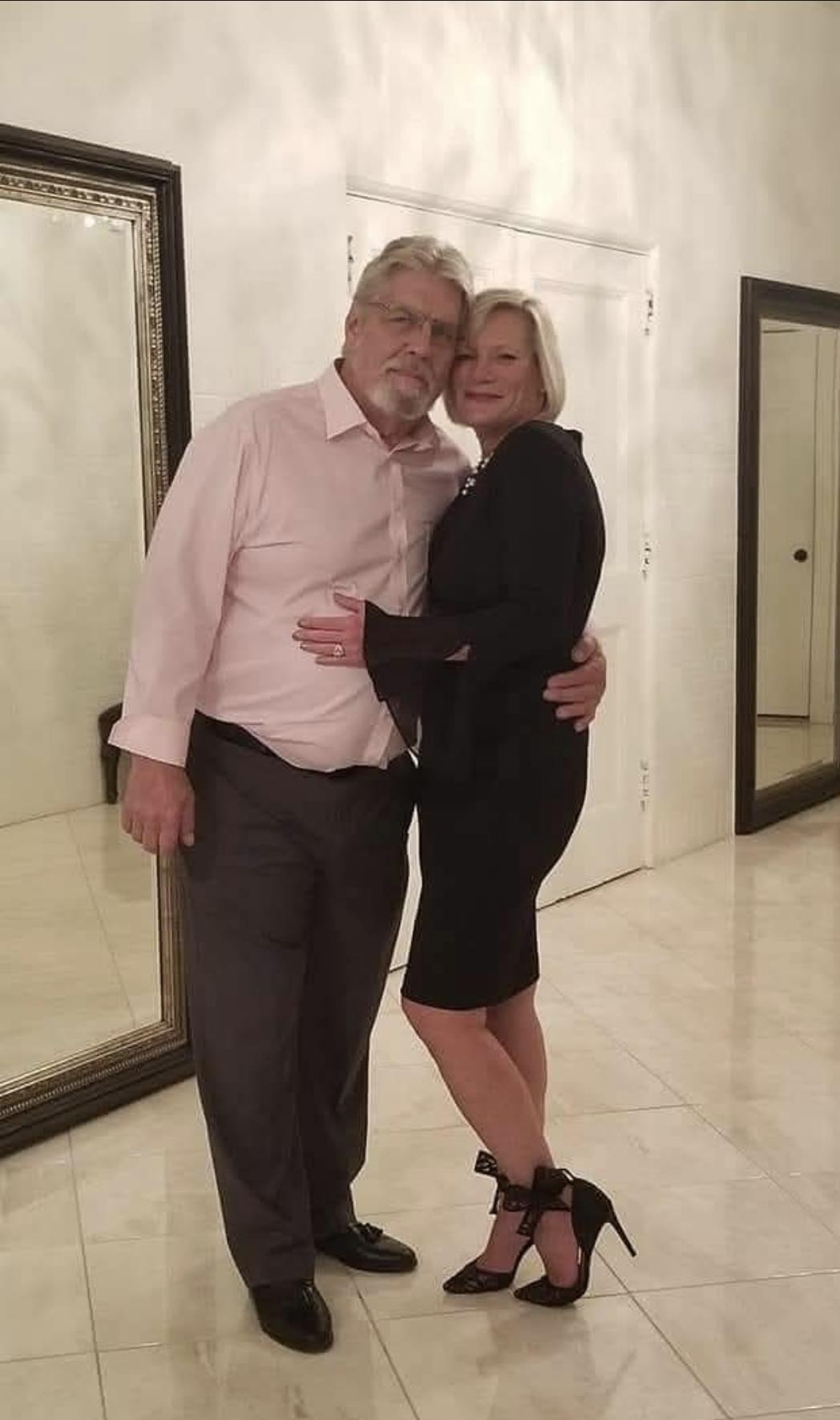 Man and woman pose intimately in a stylish indoor space with mirrors, clearly enjoying the moment.