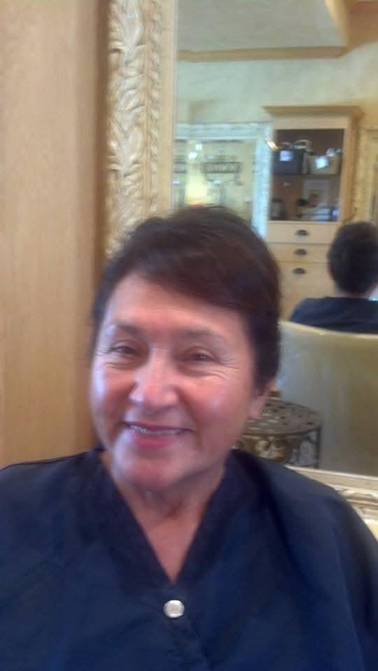 Woman with short hair showing a joyful expression while sitting in a salon chair.
