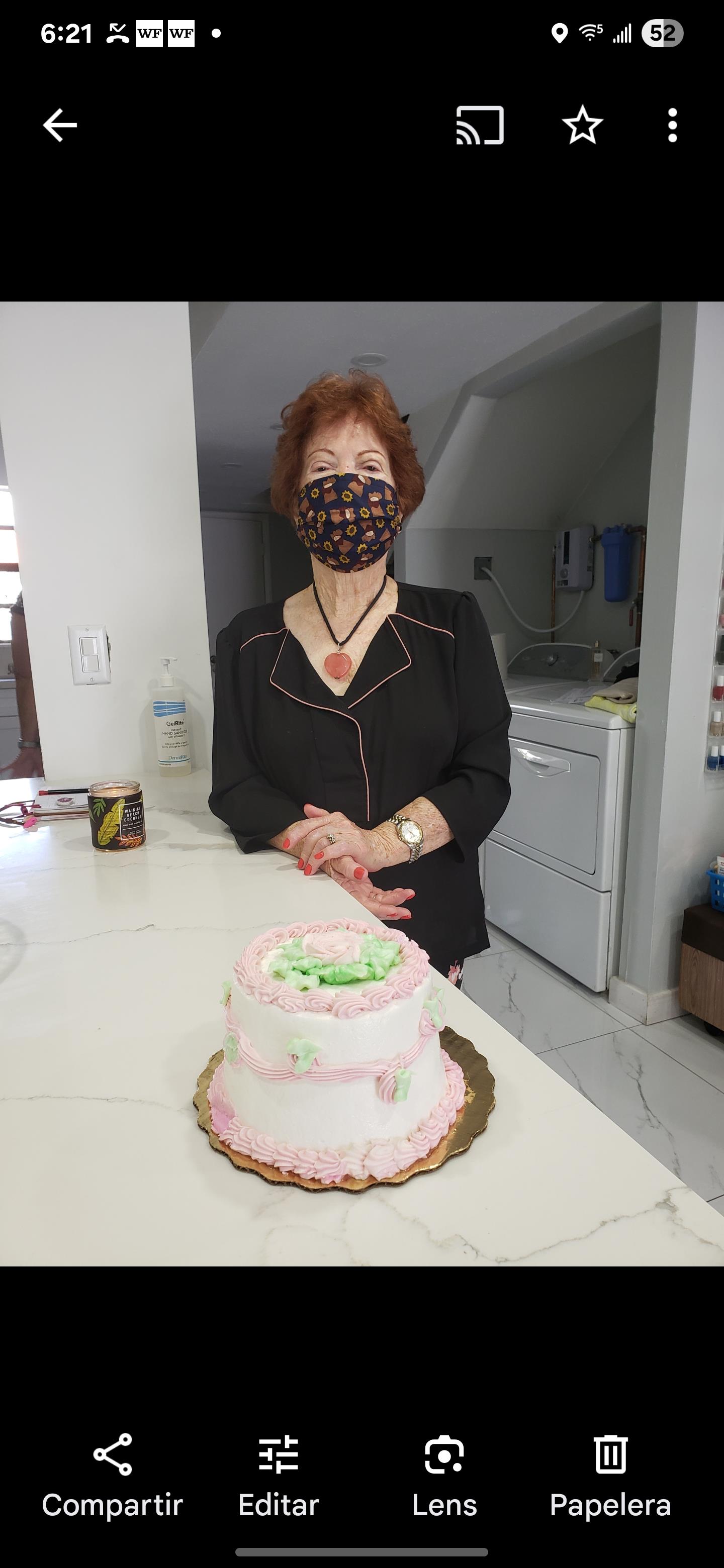 A smiling woman beside a decorated cake in a cozy kitchen at a festive gathering.