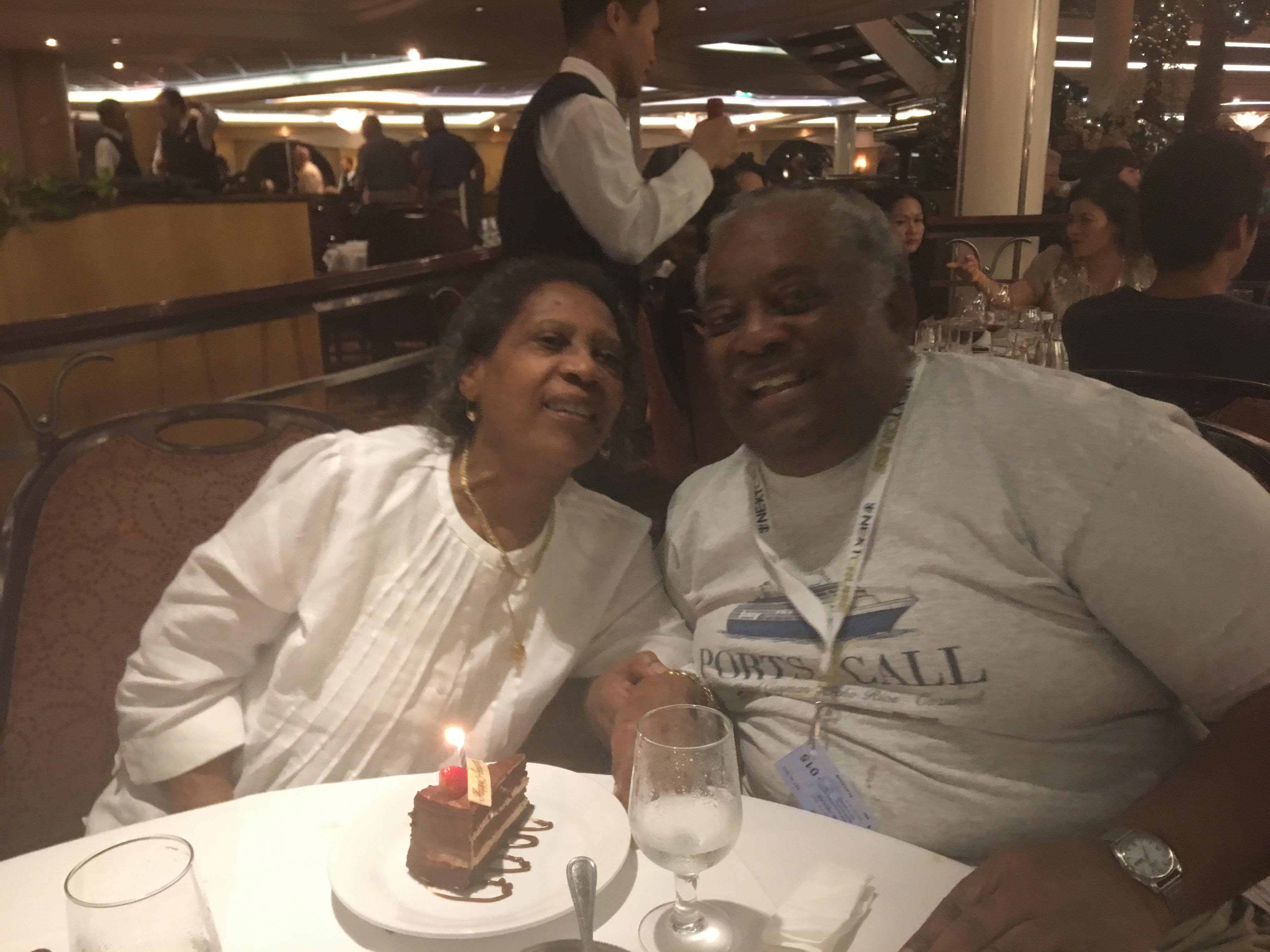 Couple enjoys a festive moment together at a restaurant, celebrating with cake and laughter.