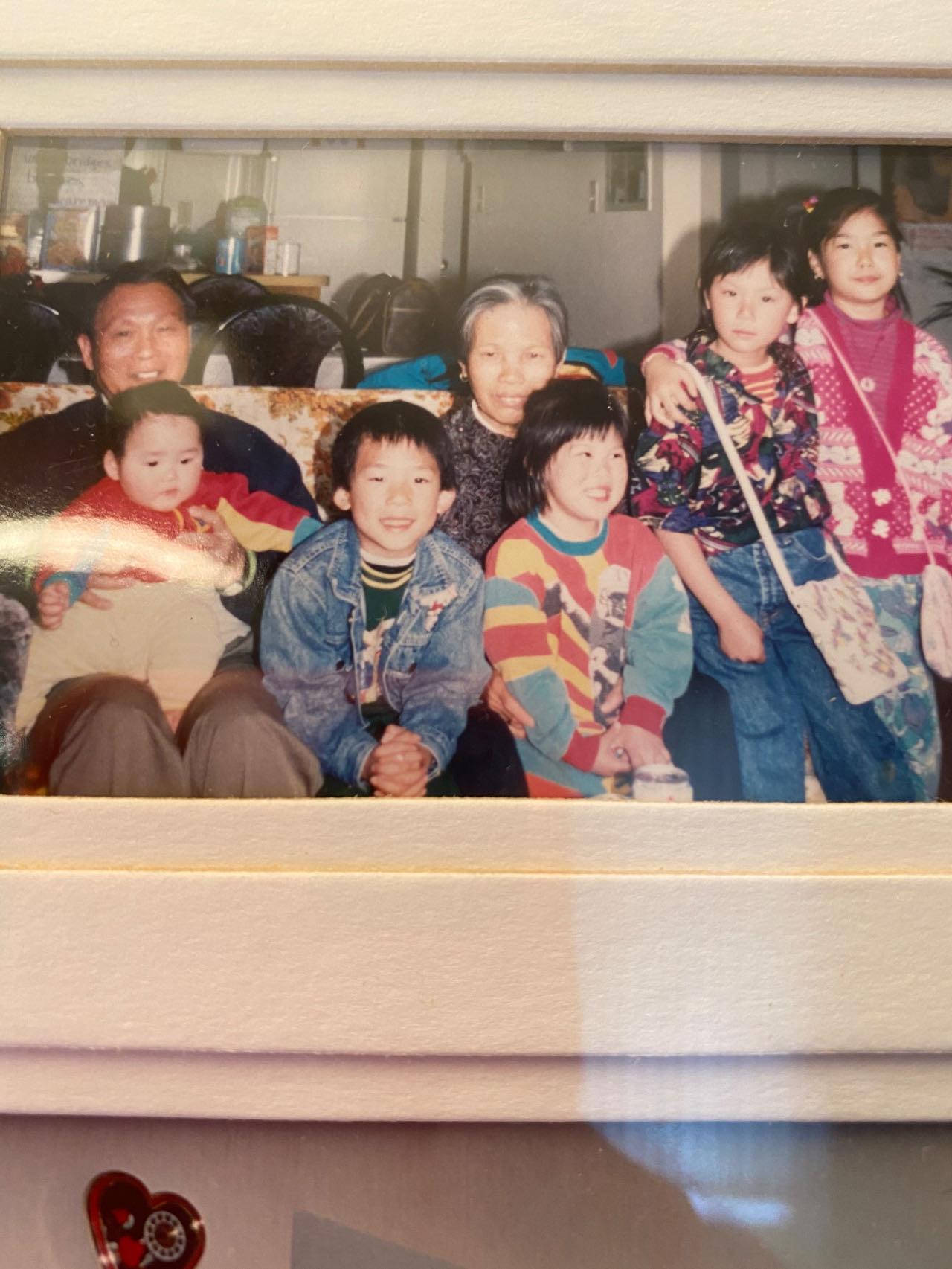 Children smile and play while seated with their grandparents in a warm, inviting living room.