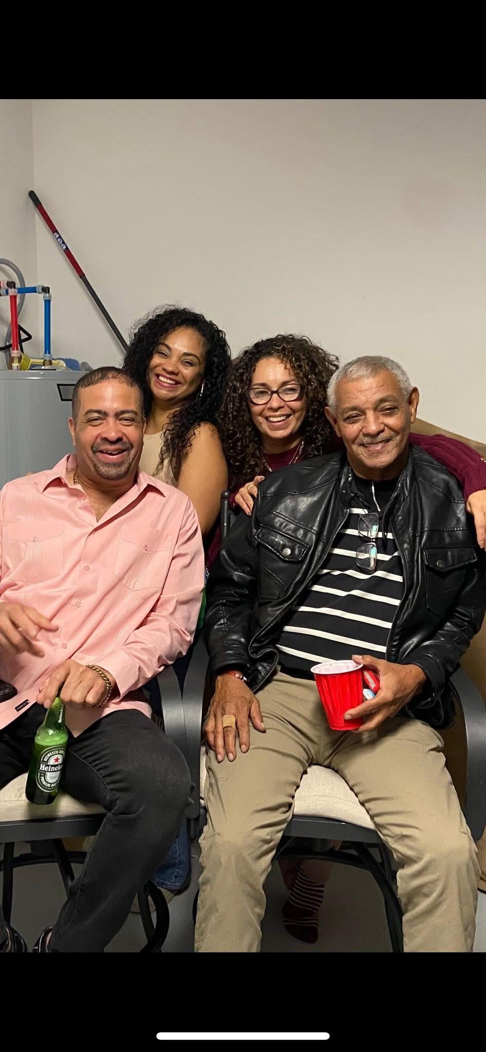 Four friends smile and relax together in a cozy indoor setting during a social gathering.