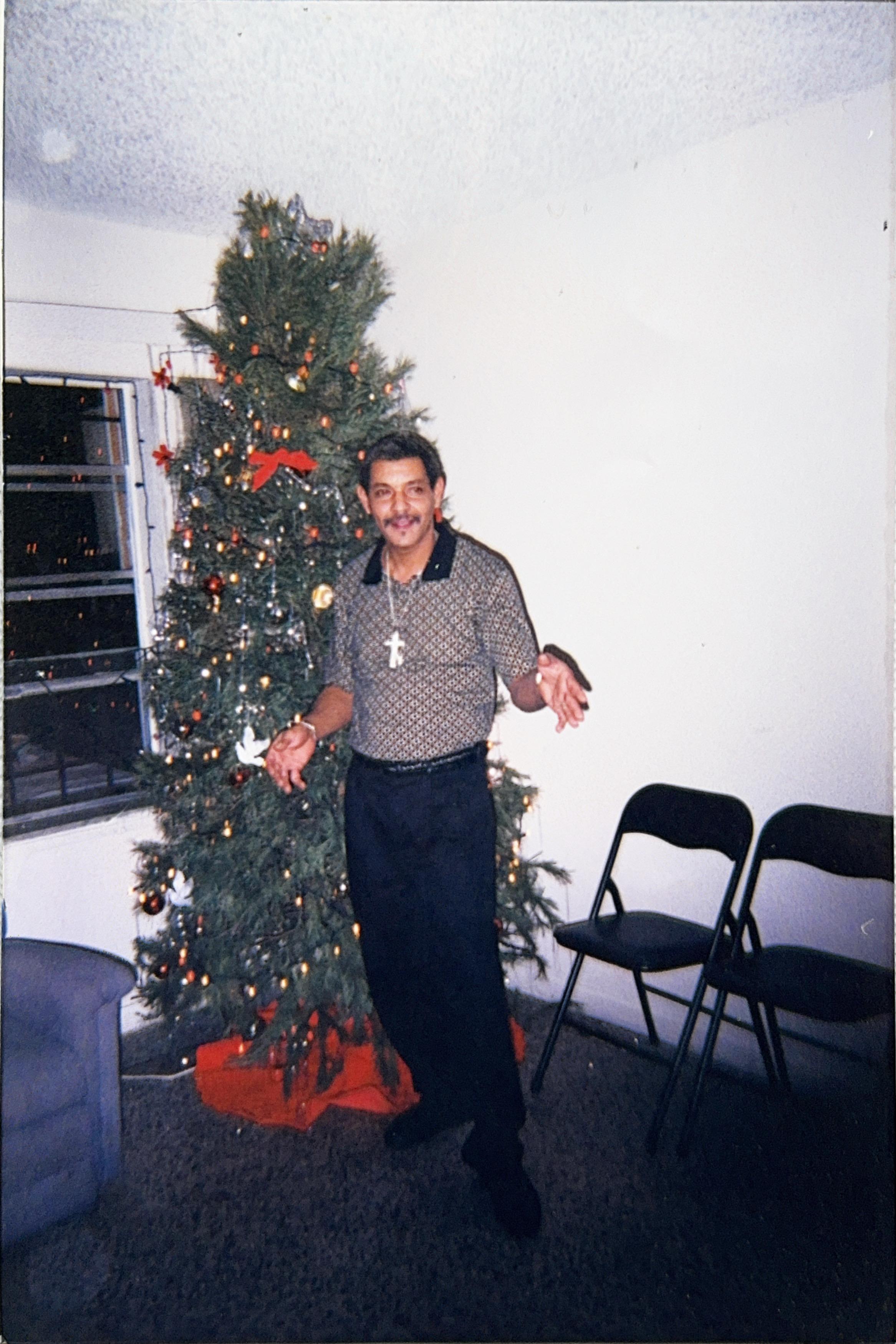 A man poses cheerfully in a decorated living room during the Christmas season.
