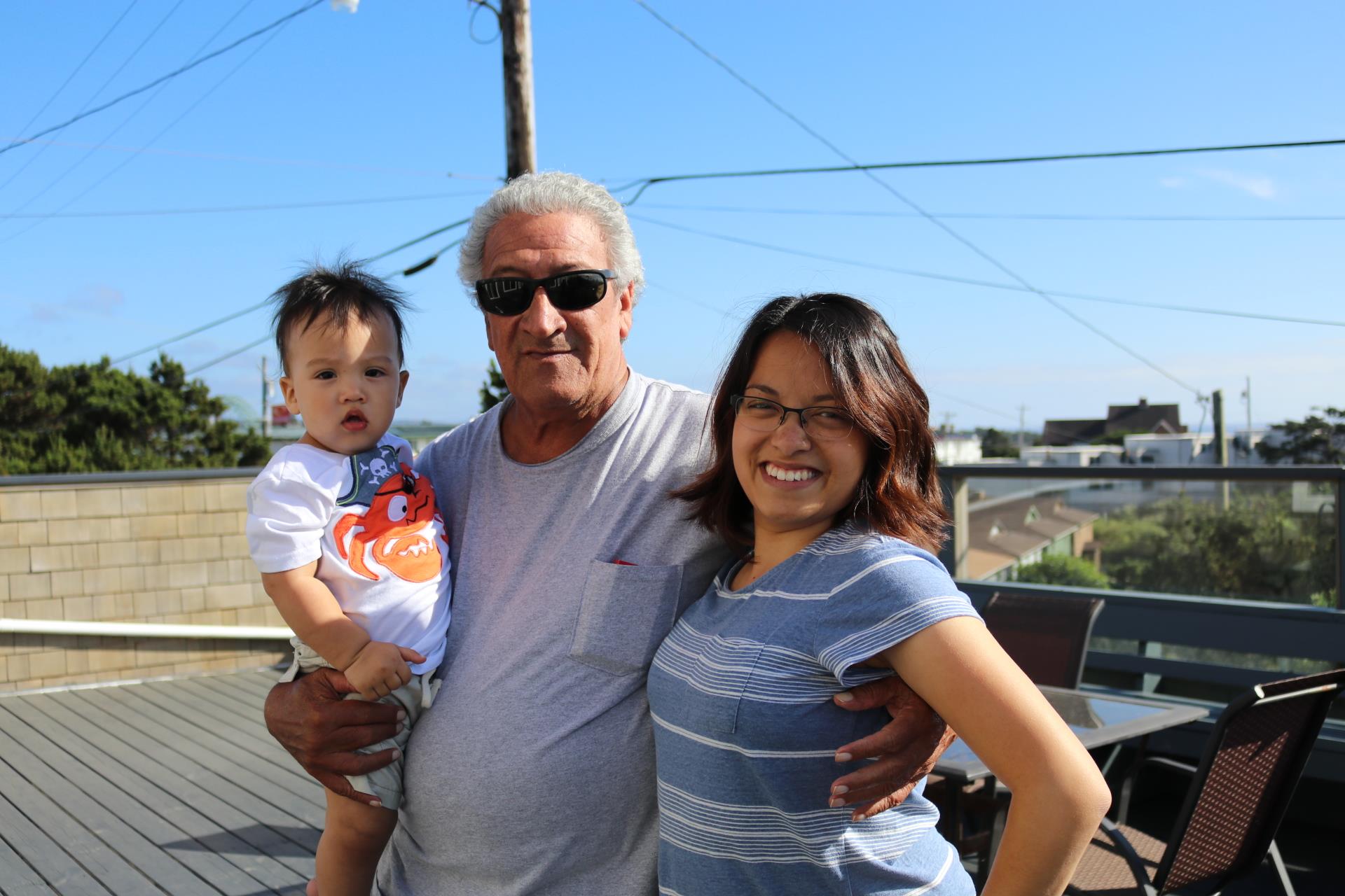 A joyful family moment featuring a man holding a child and a woman beside them outdoors.