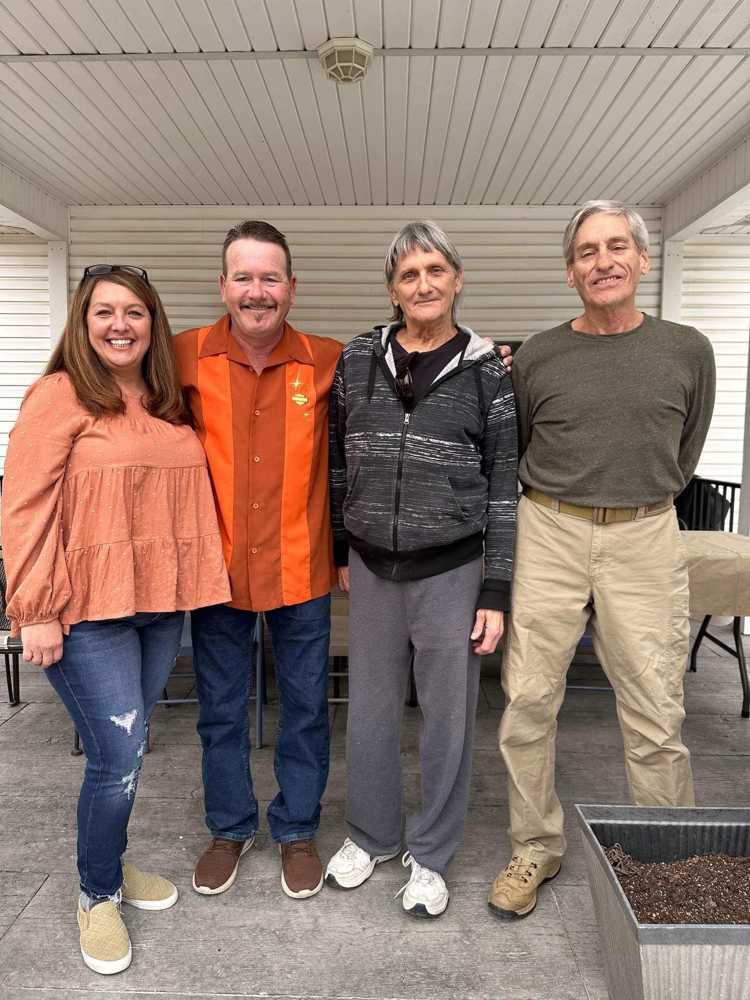 Friends gather on a covered porch, sharing smiles and good company during the afternoon.