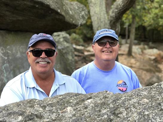 Two men wearing blue shirts and sunglasses