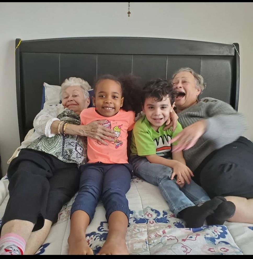Elderly women and young children share laughter and warmth during a cherished family moment at home.